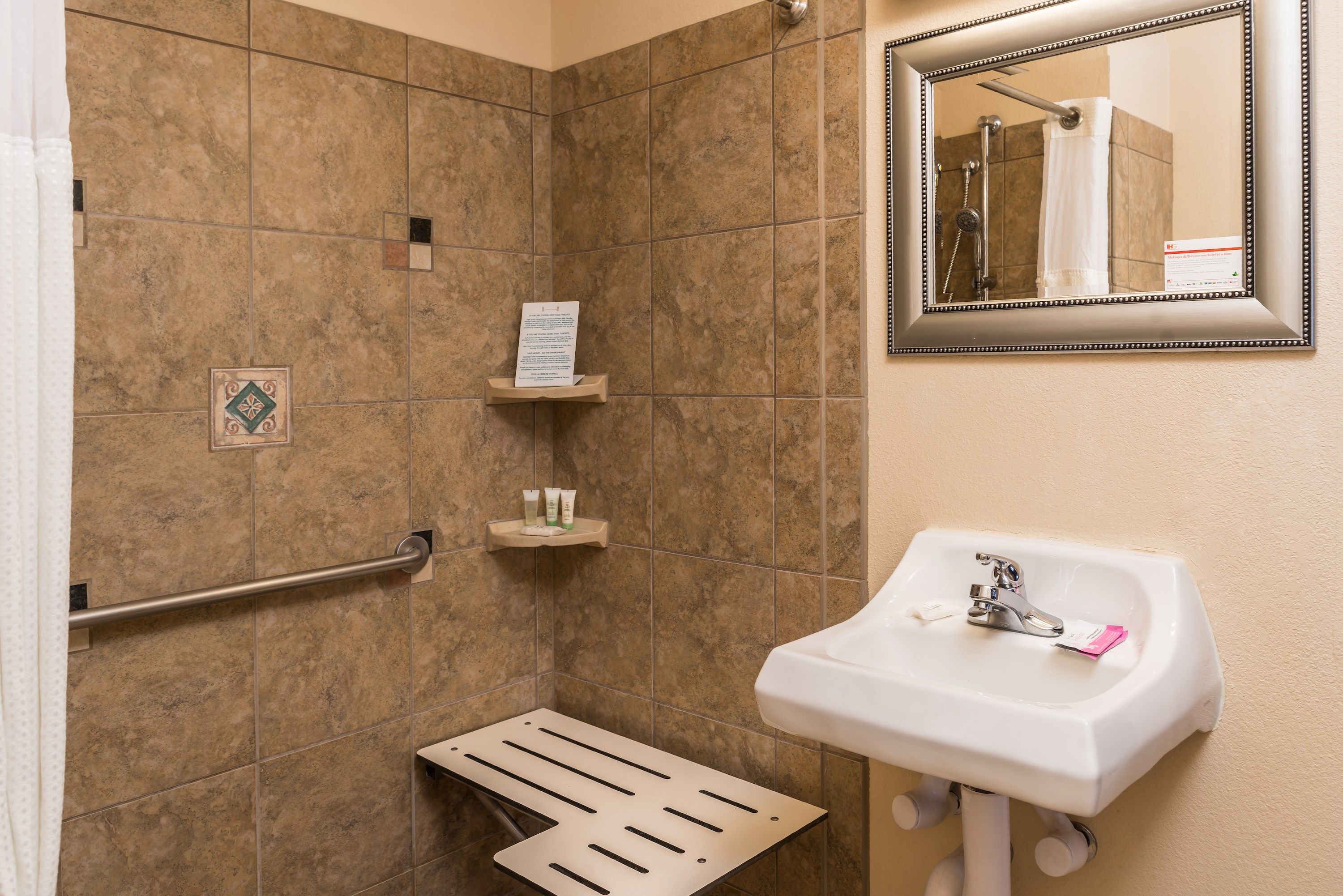 image Accessible bathroom with roll-in shower, grab bar, and shower bench.