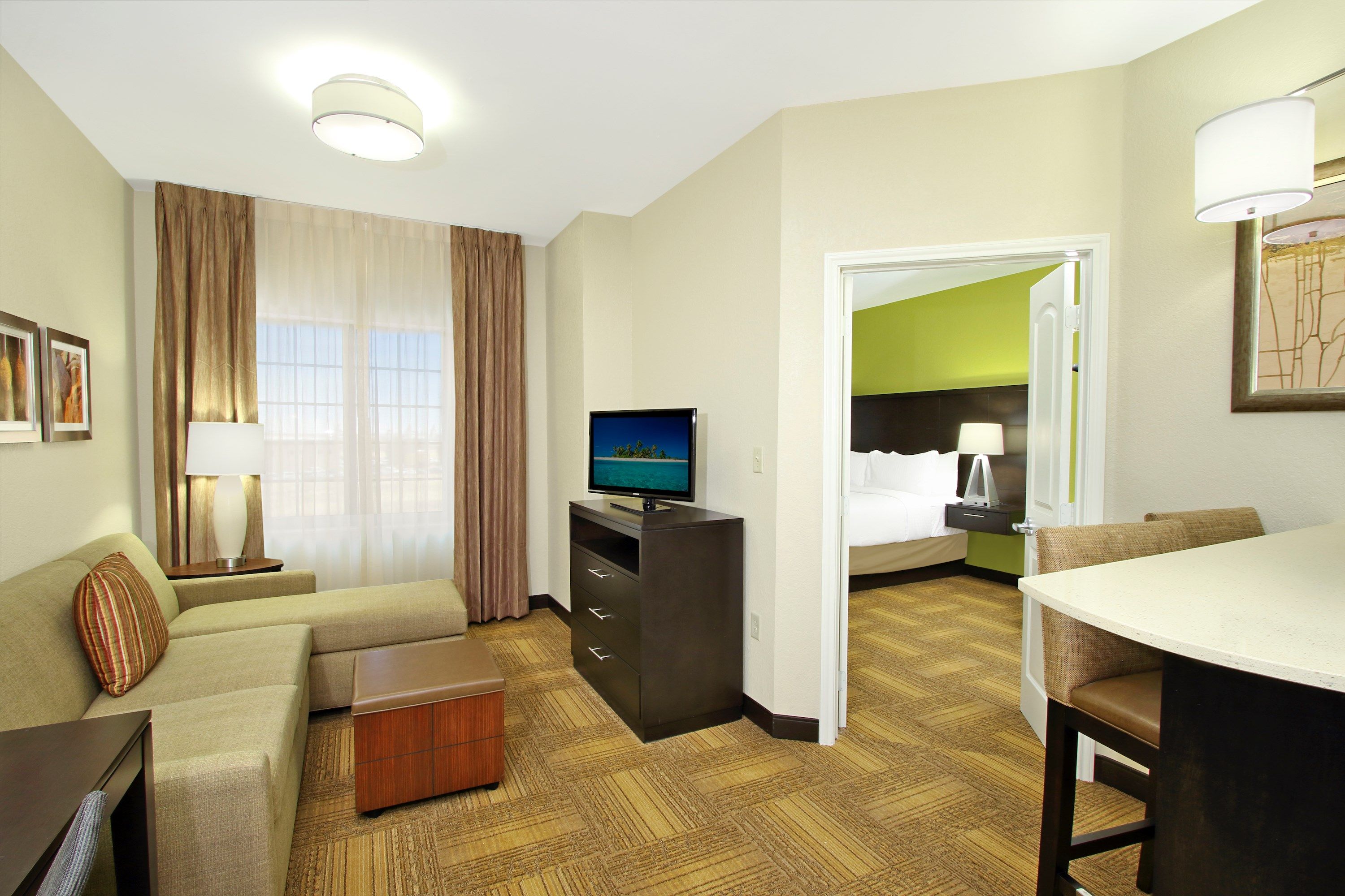 image Living area with sofa, flat-screen TV, and view into bedroom.
