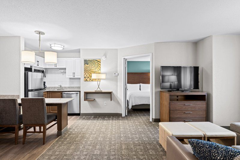 image Open-plan living and dining area with flat-screen TV and kitchen views.