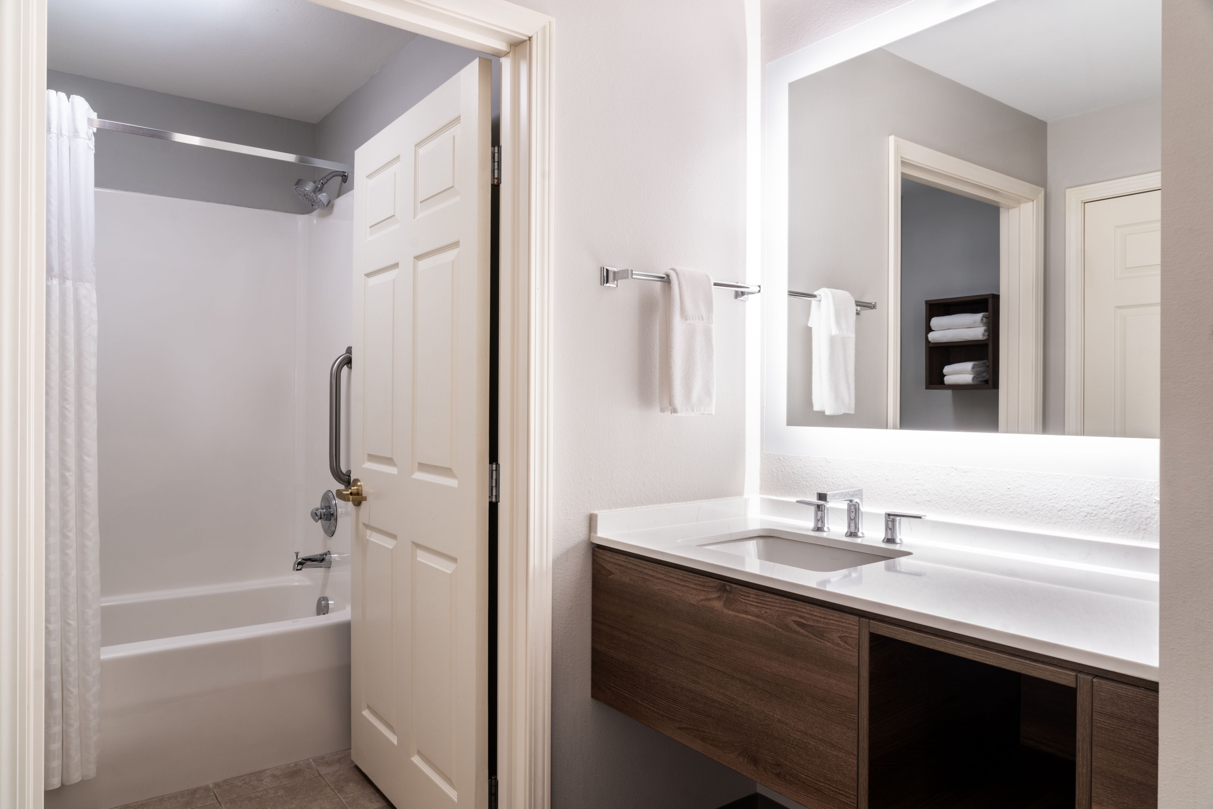 image Bright bathroom with modern fixtures and a large mirror.