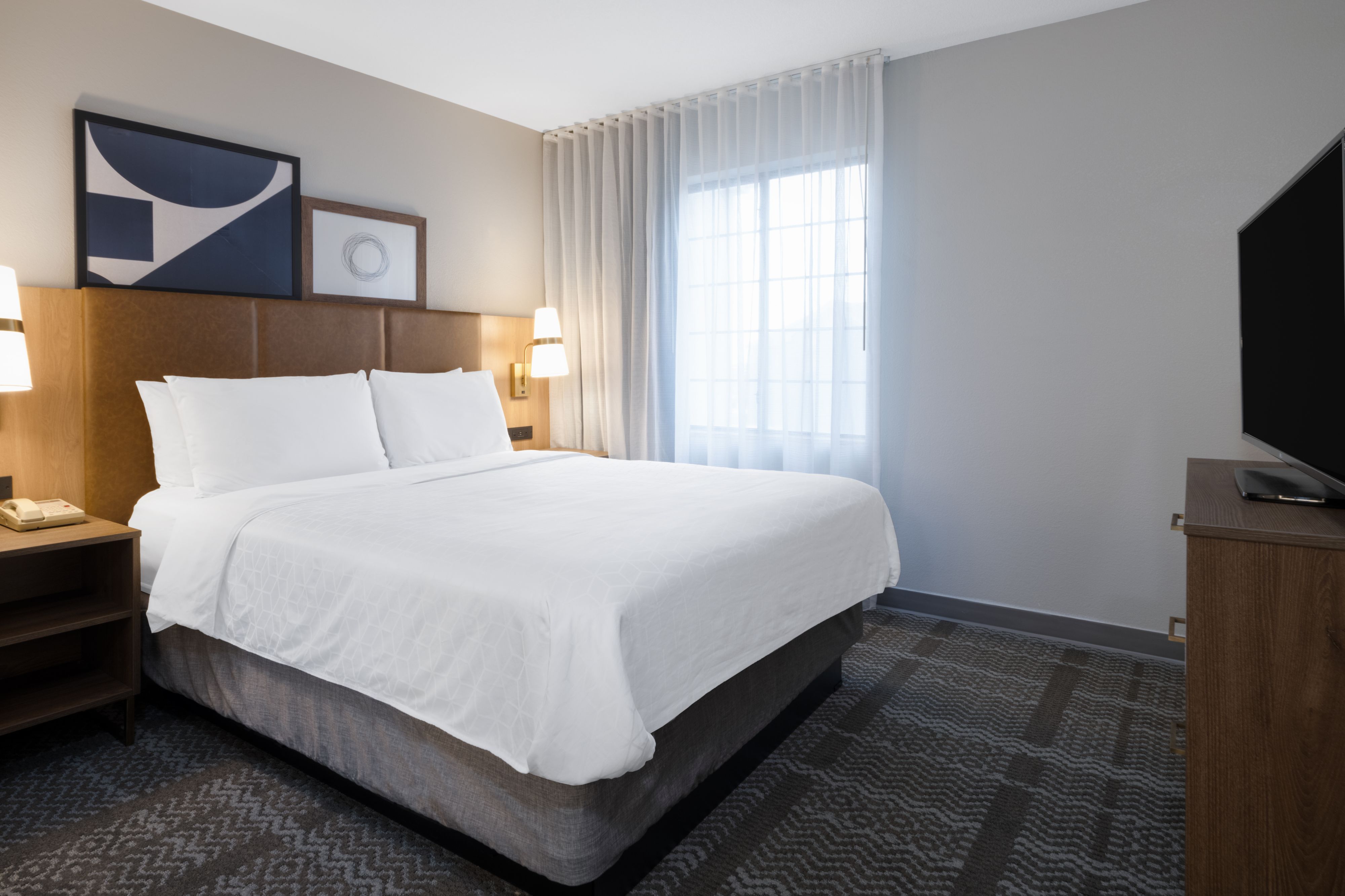 image Well-appointed queen bedroom with modern decor and TV.