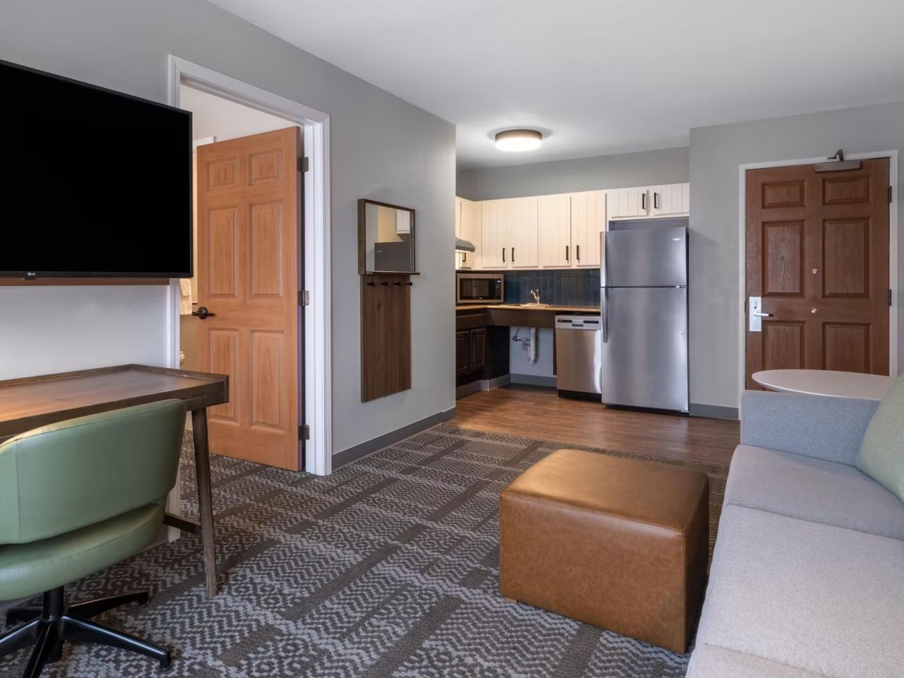 image Living area with sofa, desk, and kitchen.