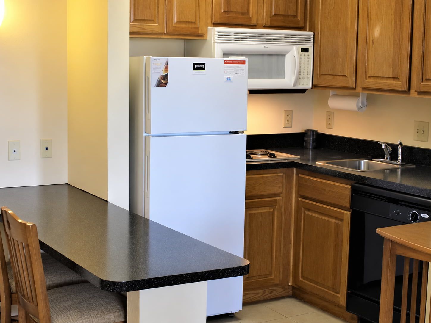 image Fully equipped kitchen with a full-size refrigerator, microwave, stovetop, dishwasher, and breakfast bar.