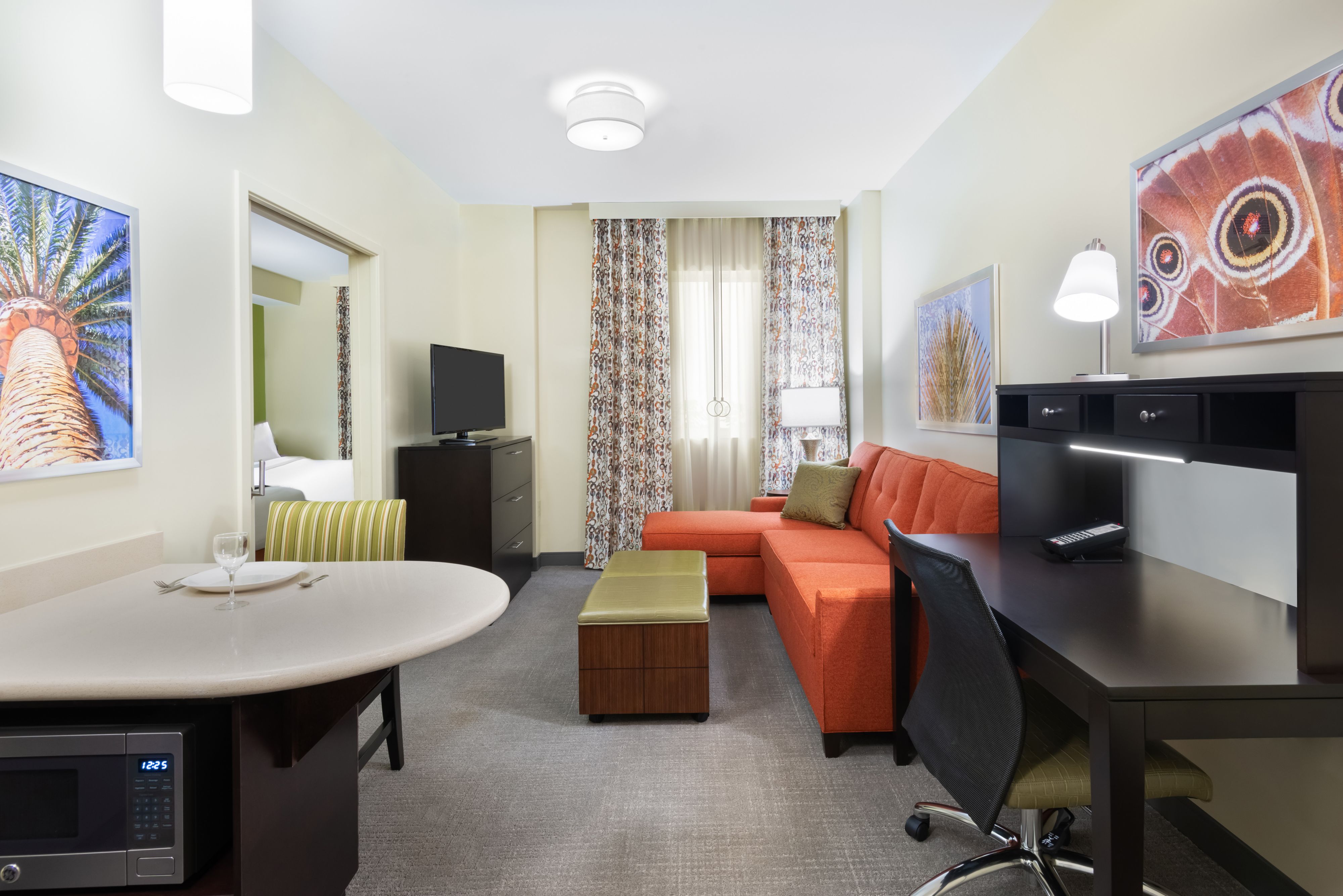 image Relax on the spacious orange sofa, with a cozy ambiance and views of vibrant art adorning the walls.