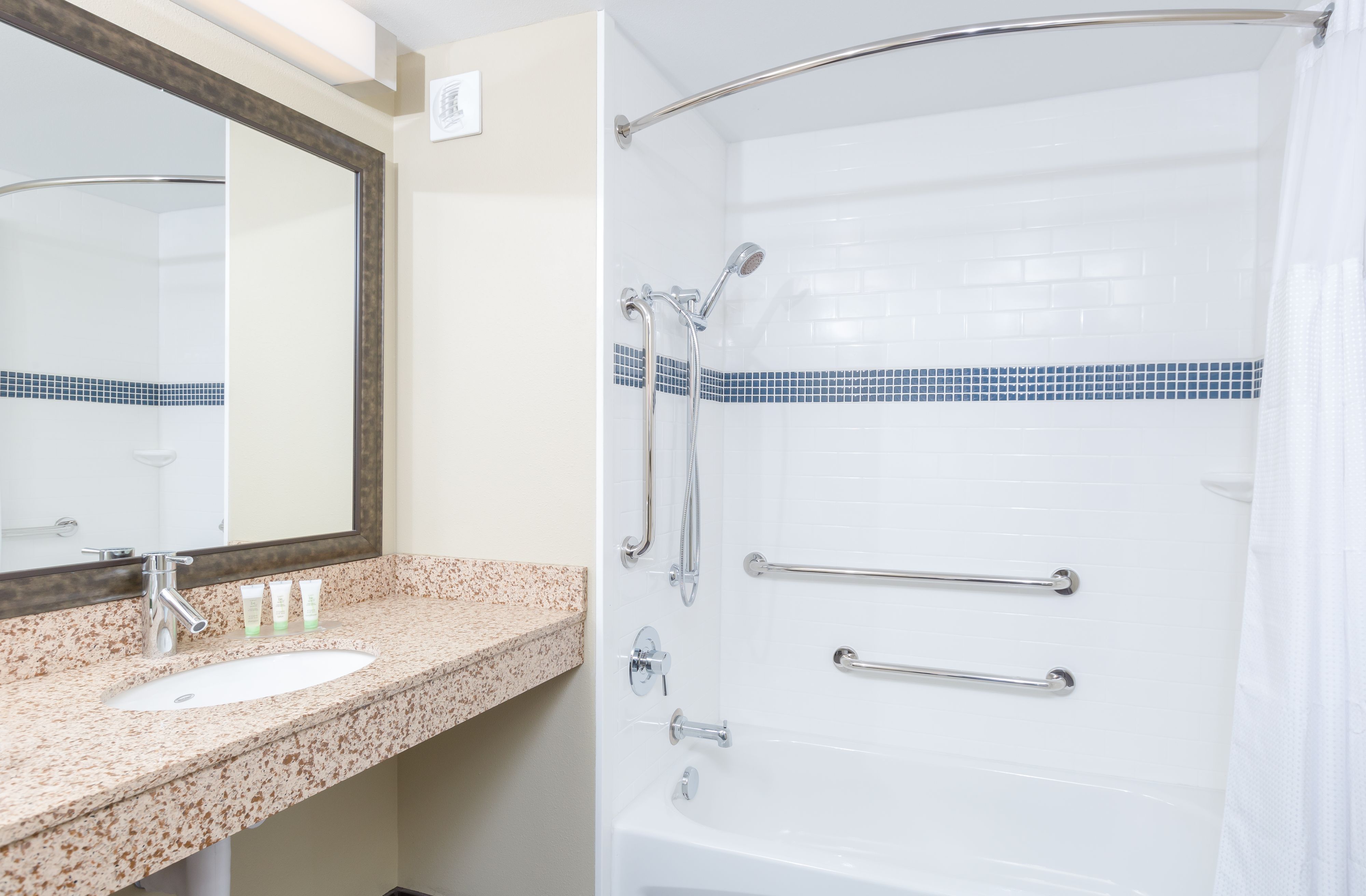 image Accessible bathroom with bathtub, grab bars, and handheld showerhead.
