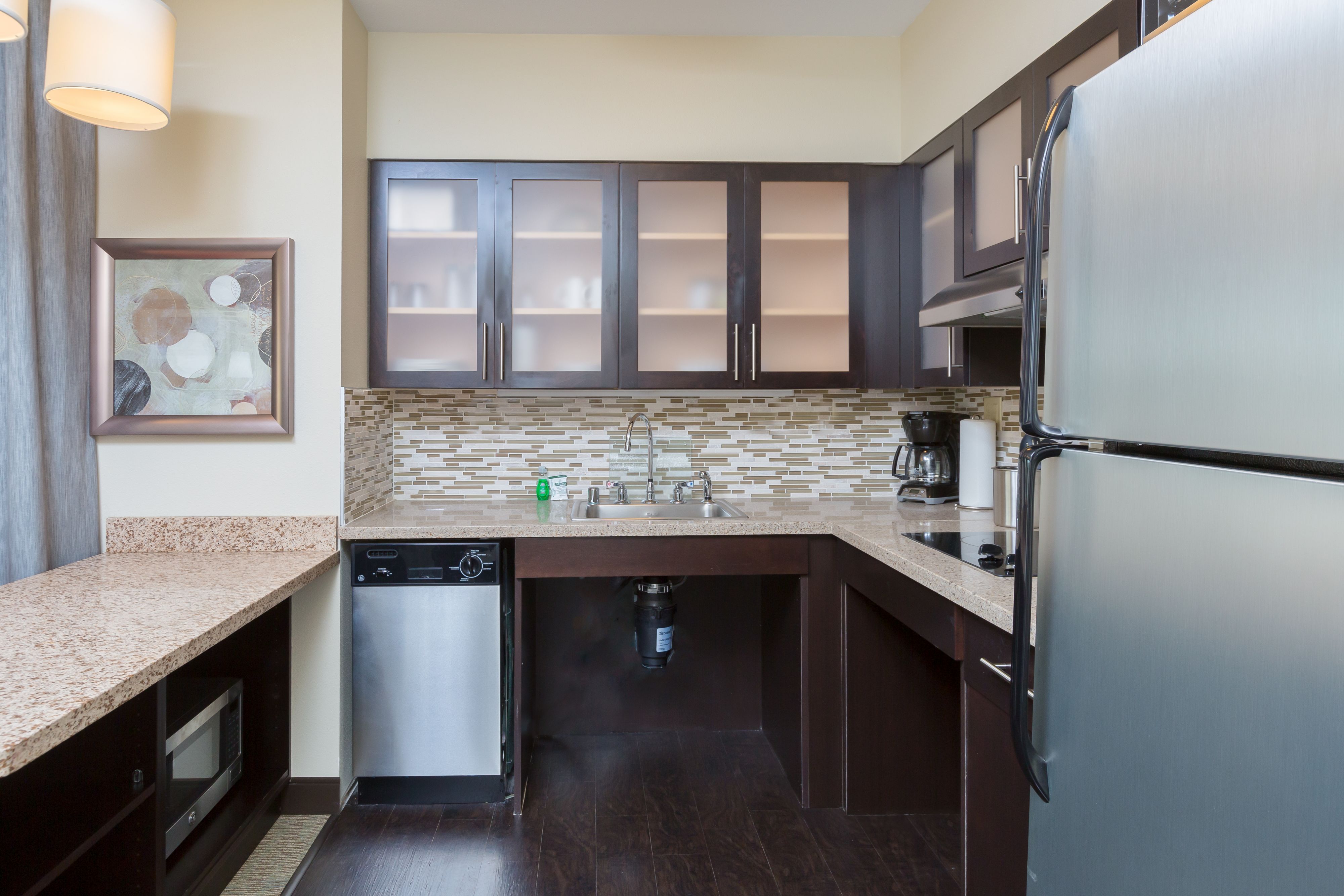 image Modern kitchen with granite countertops, stainless appliances, and stylish backsplash.