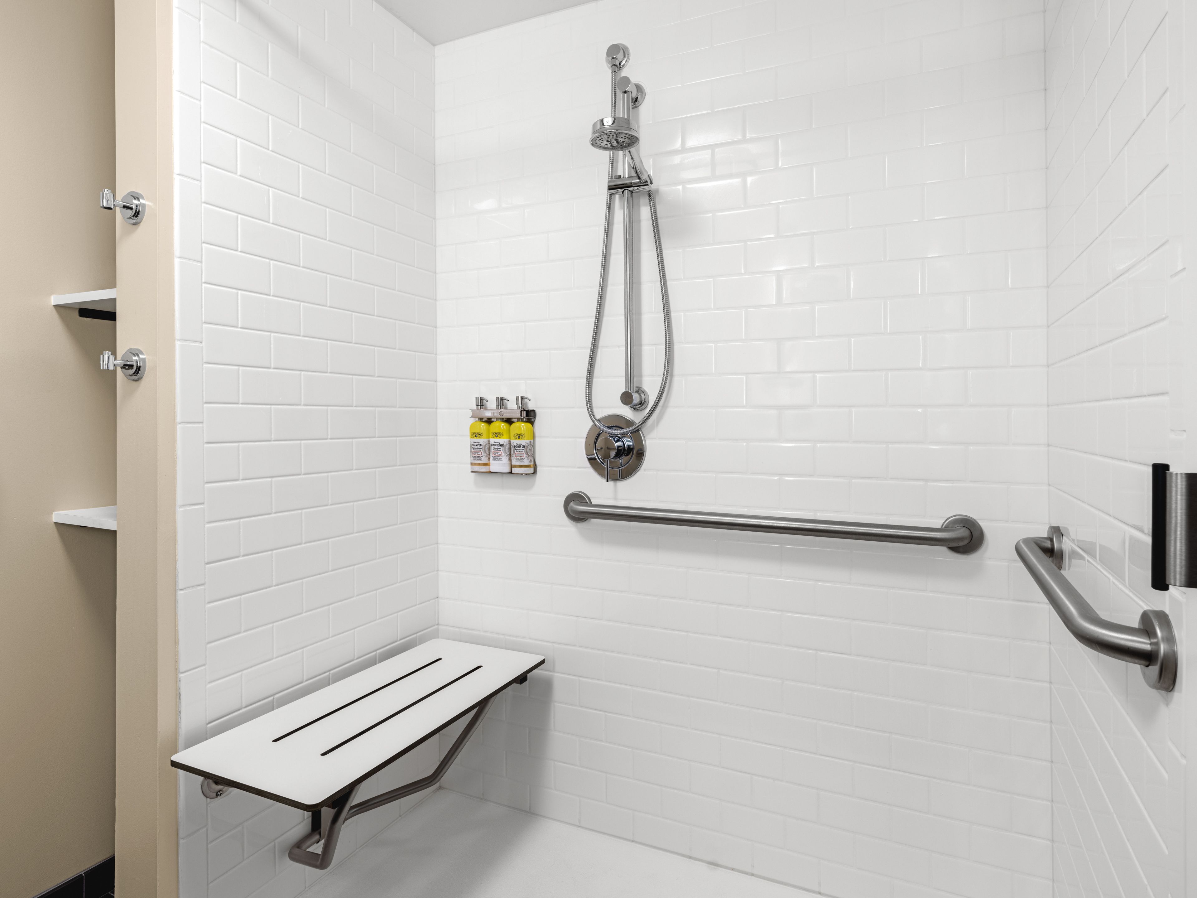 image Accessible roll-in shower with grab bars and folding bench.