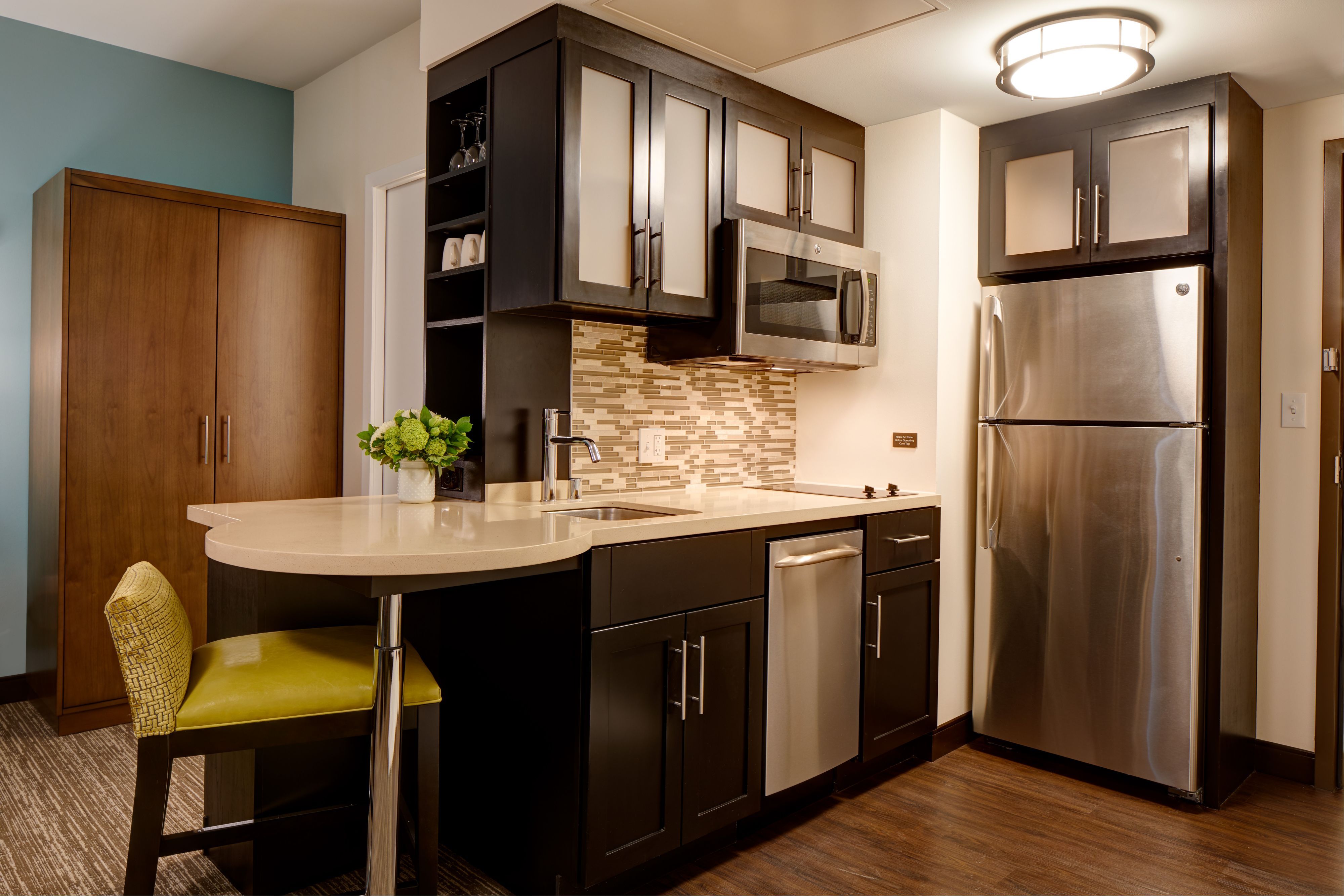 image Full kitchen with stainless appliances and seating.