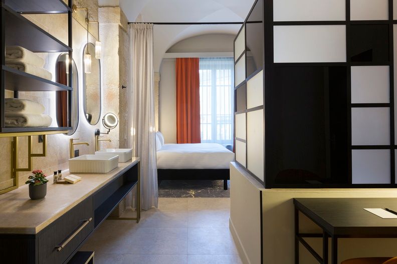 image A full view of the deluxe room's open-plan layout, combining a refined bedroom with a double vanity bathroom area separated by stylish black partitions.