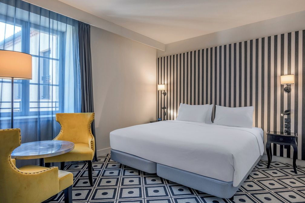 image King bed with geometric-patterned floor and striped feature wall — air conditioning included in every room.
