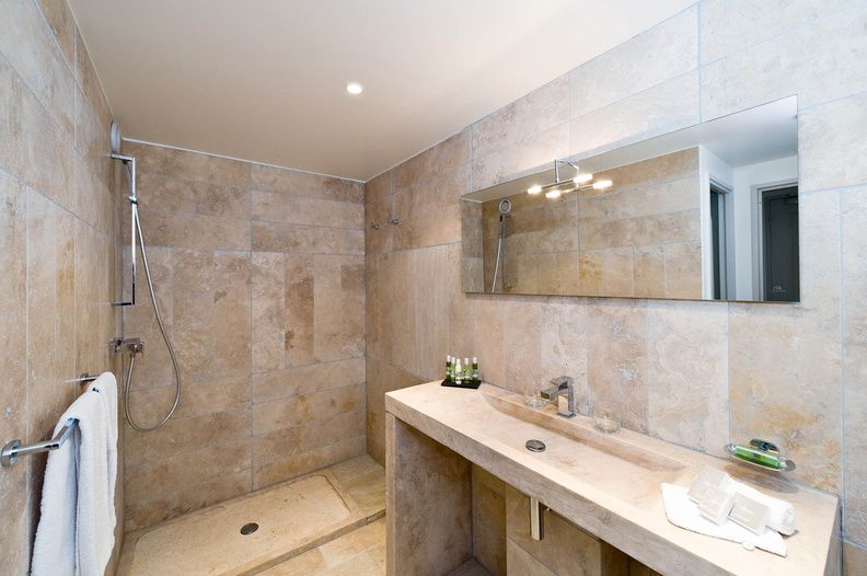 image The en-suite bathroom features a walk-in shower and warm stone-effect tiling, combining practical comfort with the understated elegance of the Provençal style.