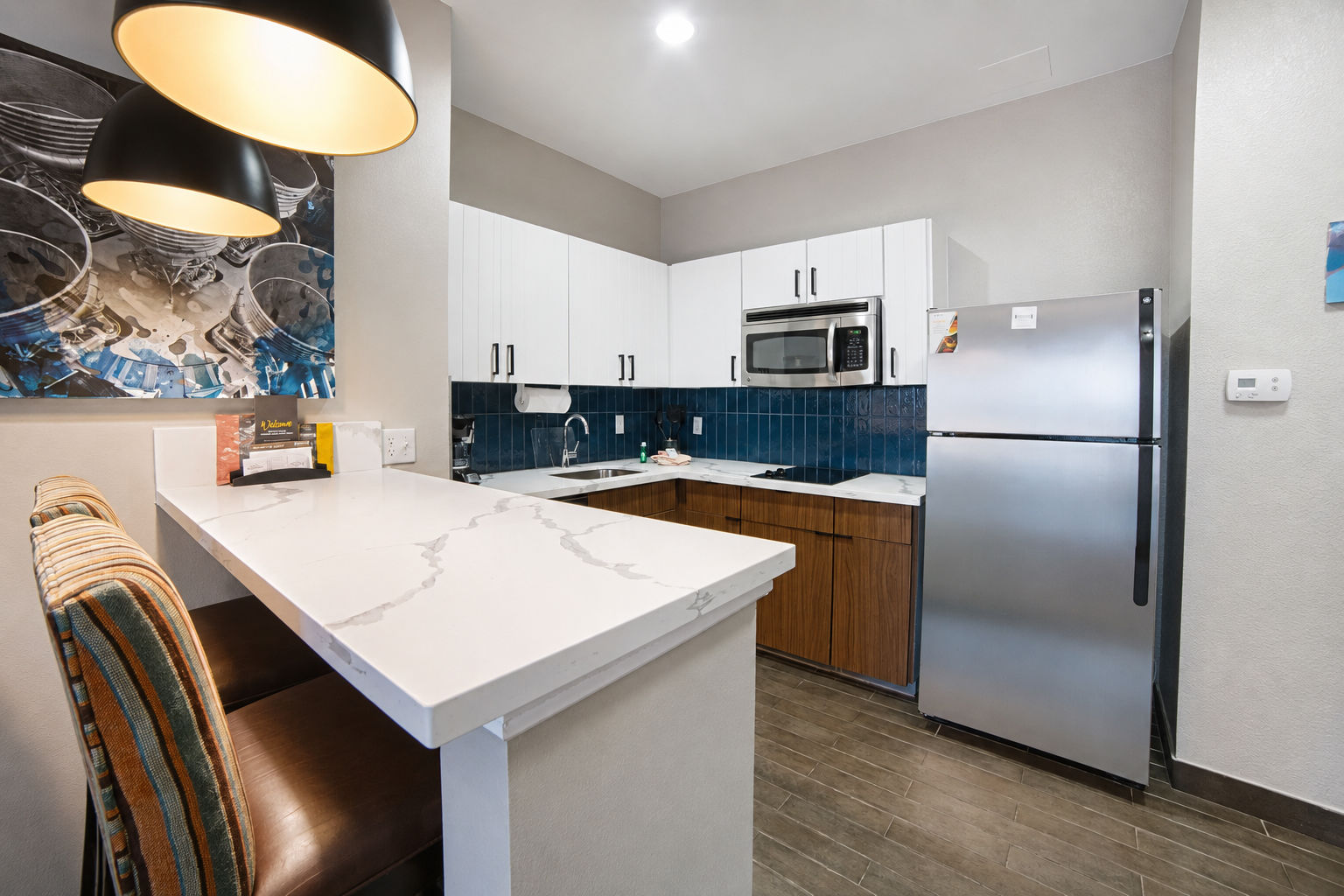 image Full kitchen with bar island, bar stools, and pendant lighting.