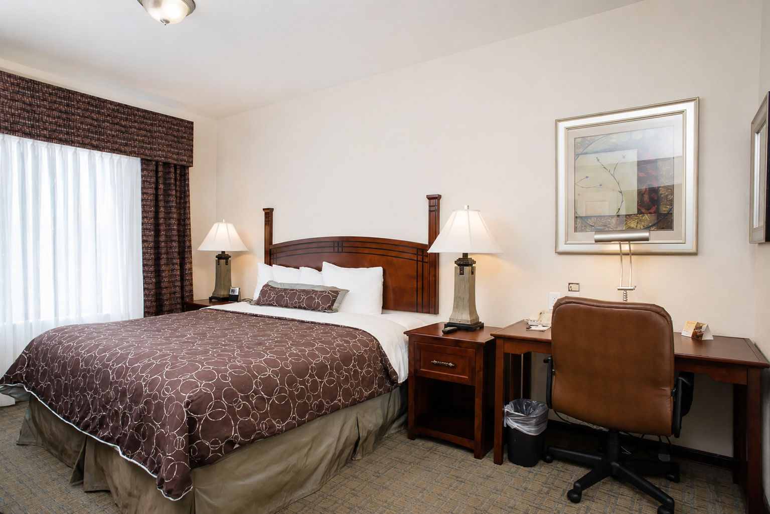image Queen bedroom with bed, work desk, and bedside lamps.