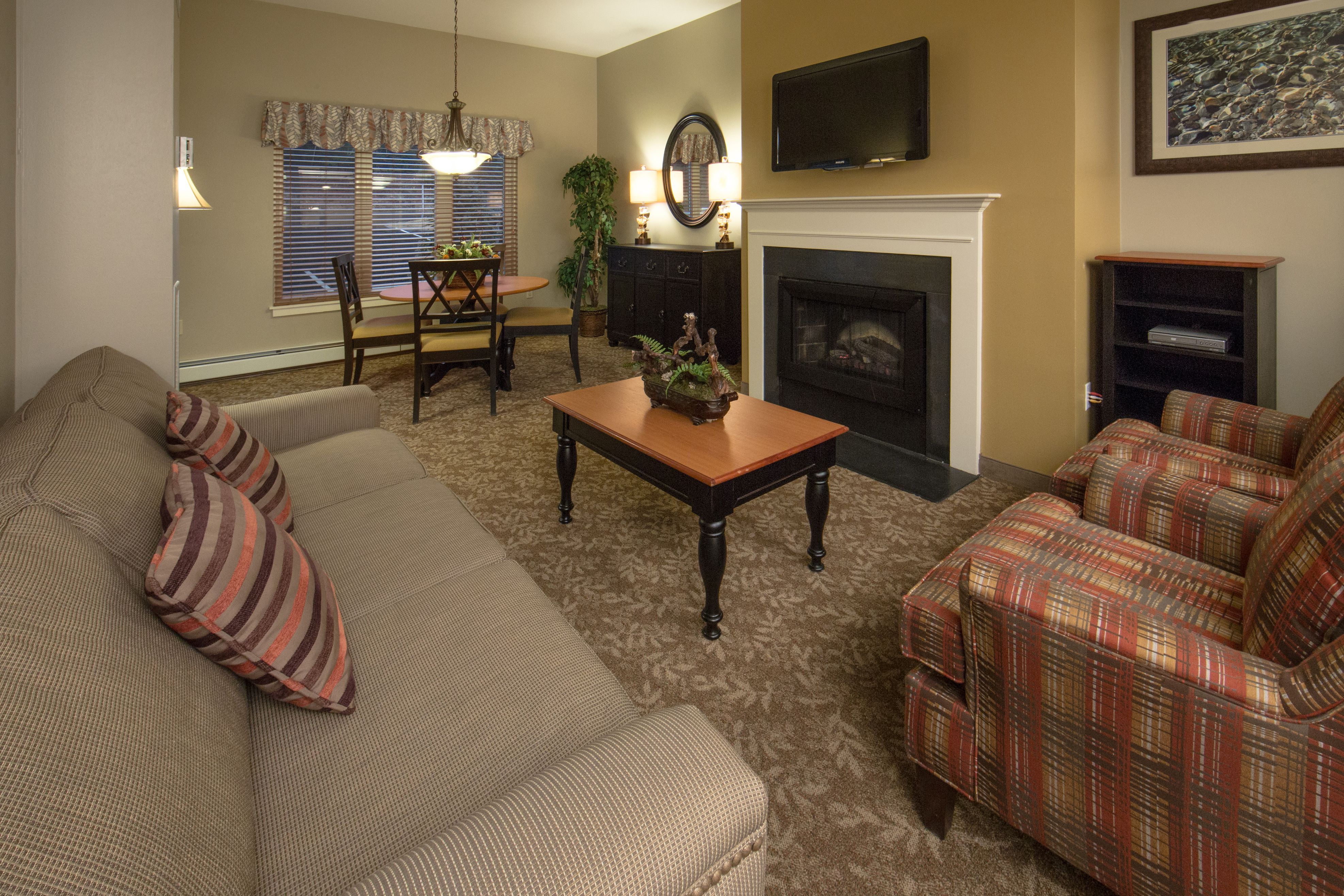 image Living area with sofa, armchairs, fireplace, and dining table.