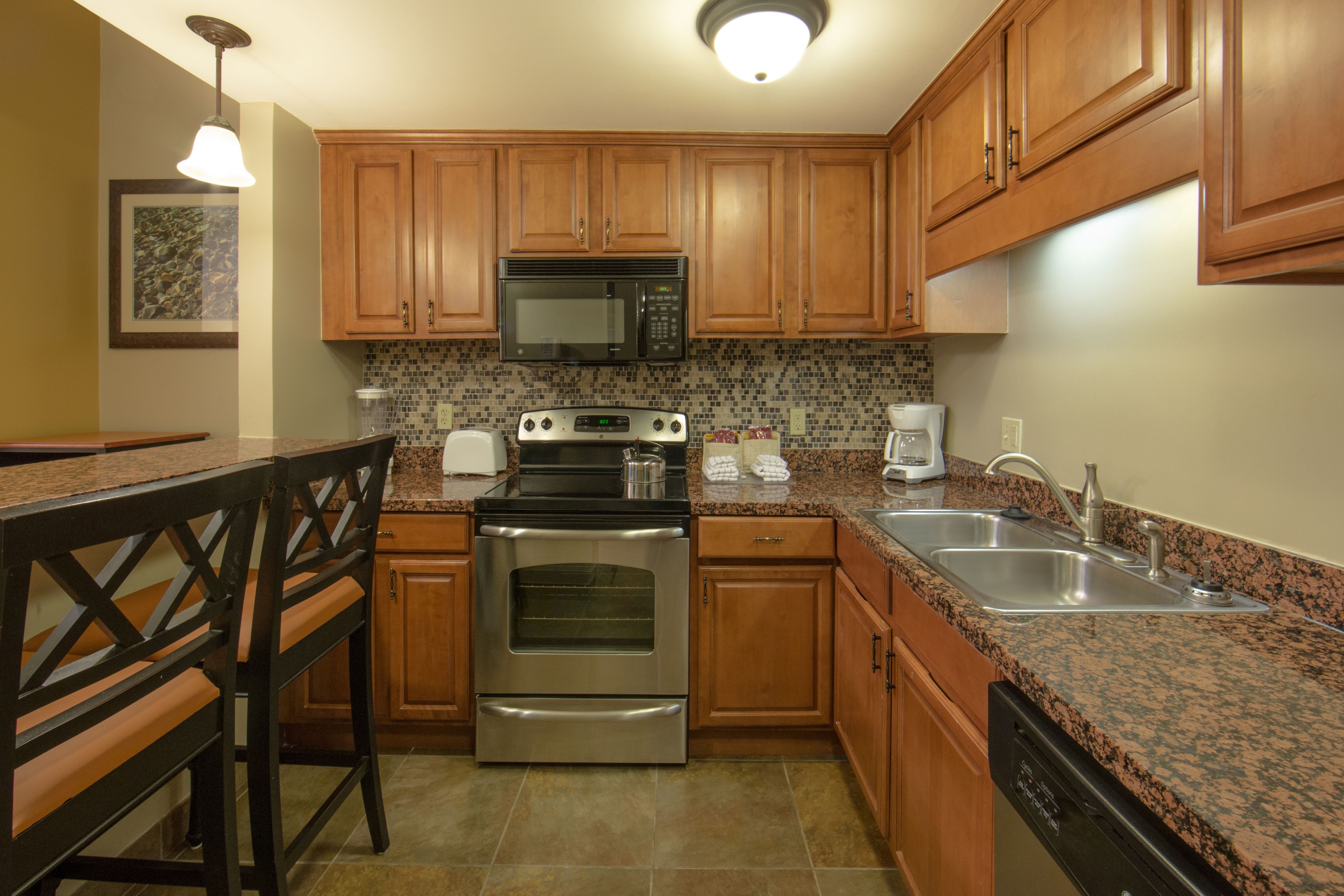 image Kitchen with wooden cabinets, stainless appliances, and bar seating.