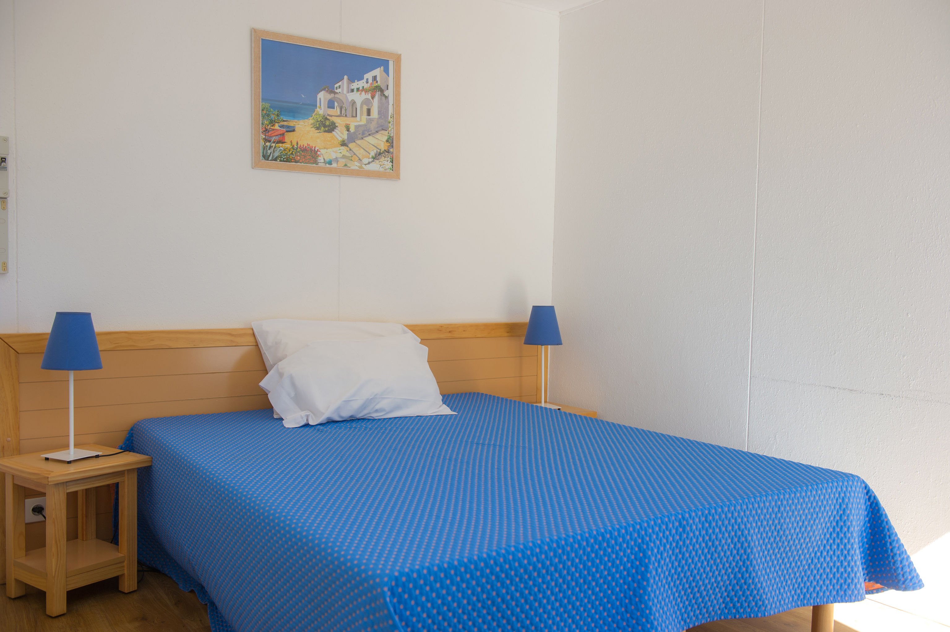 image A restful double bedroom with warm wooden furniture and a calming Mediterranean colour palette.