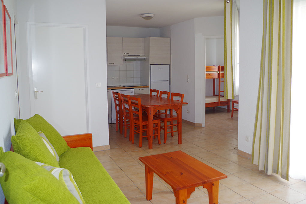 image Open-plan kitchen and dining area with wooden table, green sofa, and modern cabinetry through the archway.