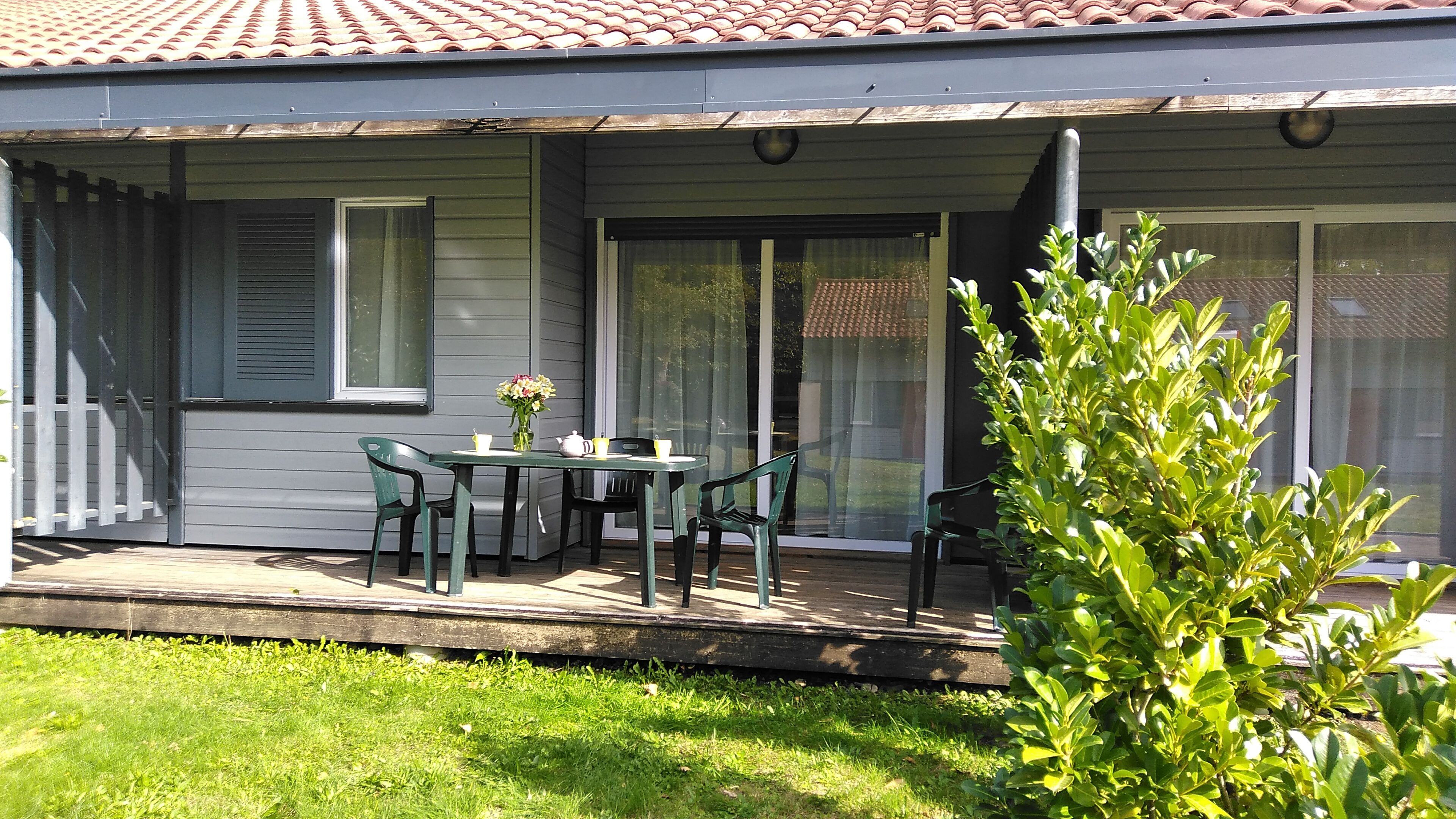 image Covered terrace with a dining table and garden chairs, steps from the lake.