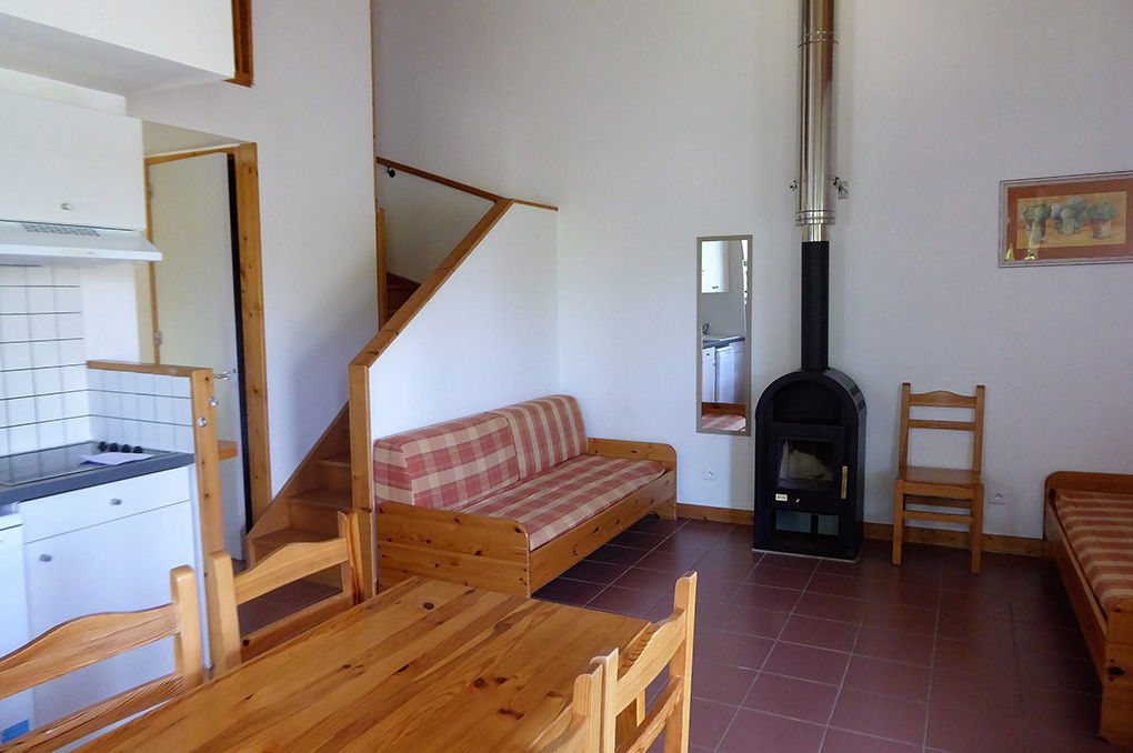 image Wood stove in the corner of the living room, with a plaid sofa and dining table.