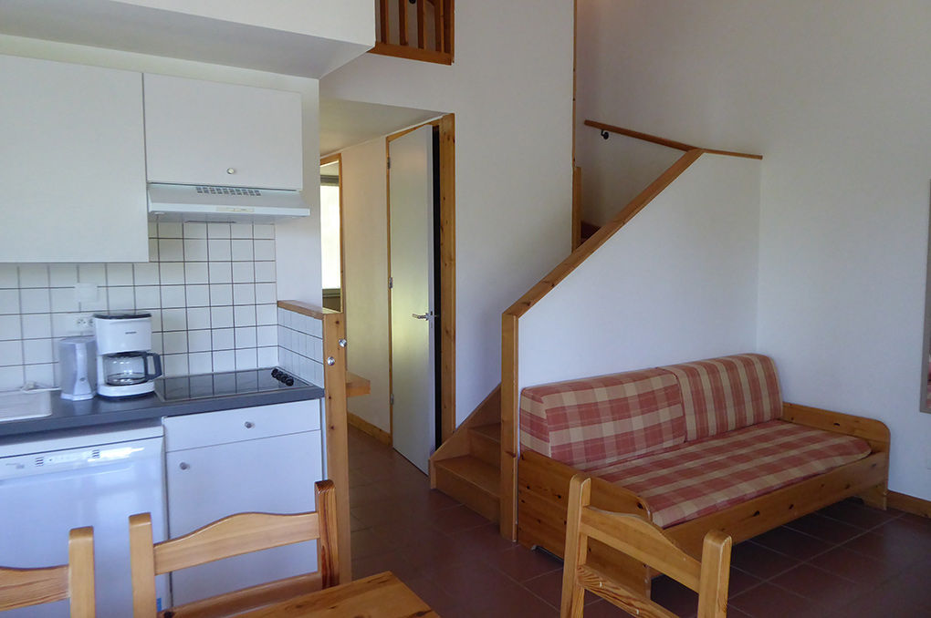 image The open living area with kitchenette, dining table, sofa beds, and stairs to the upper floor.