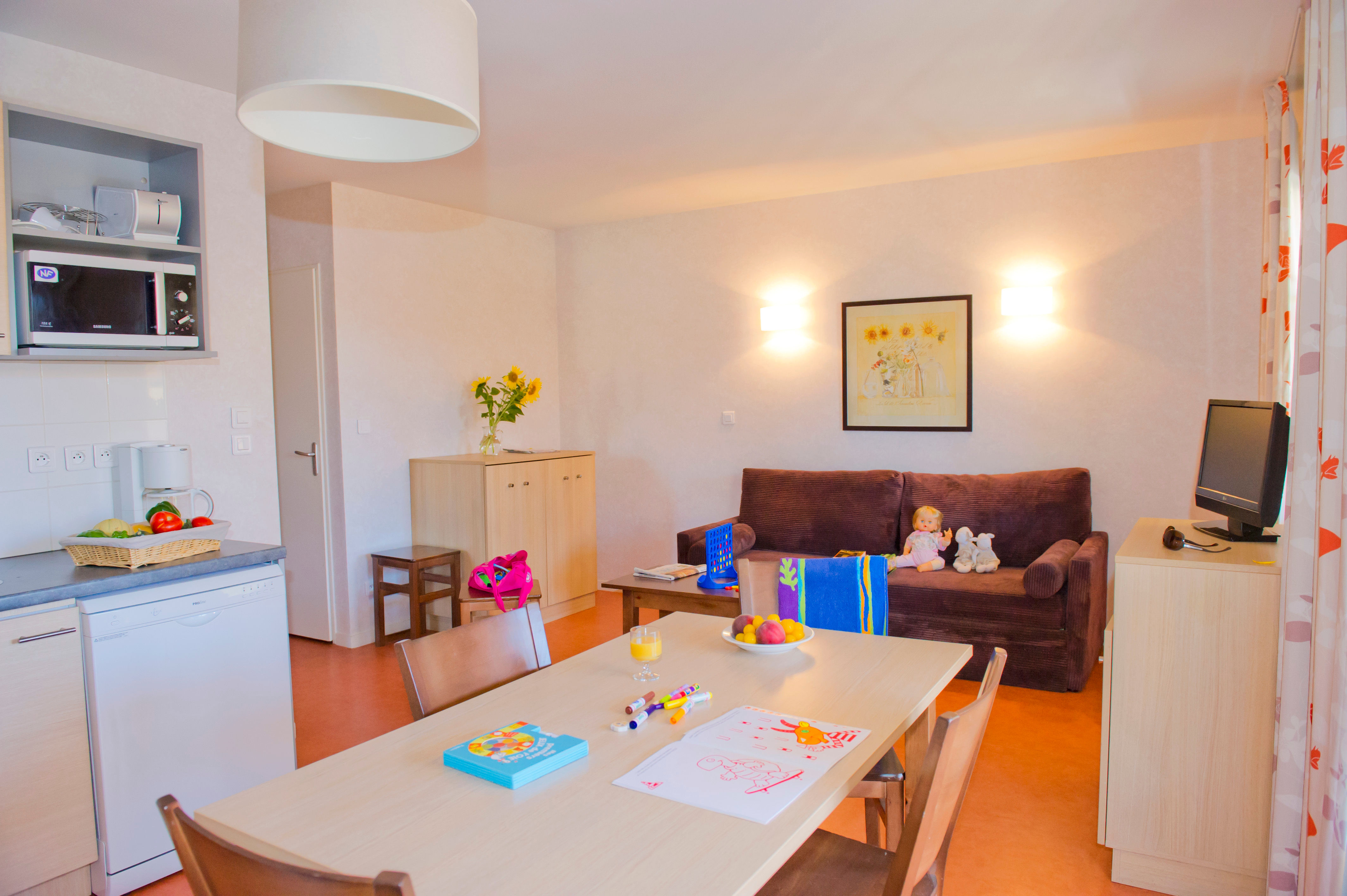 image Open-plan living and dining area with a sofa bed, four-seat dining table, microwave, and coffee maker within reach.
