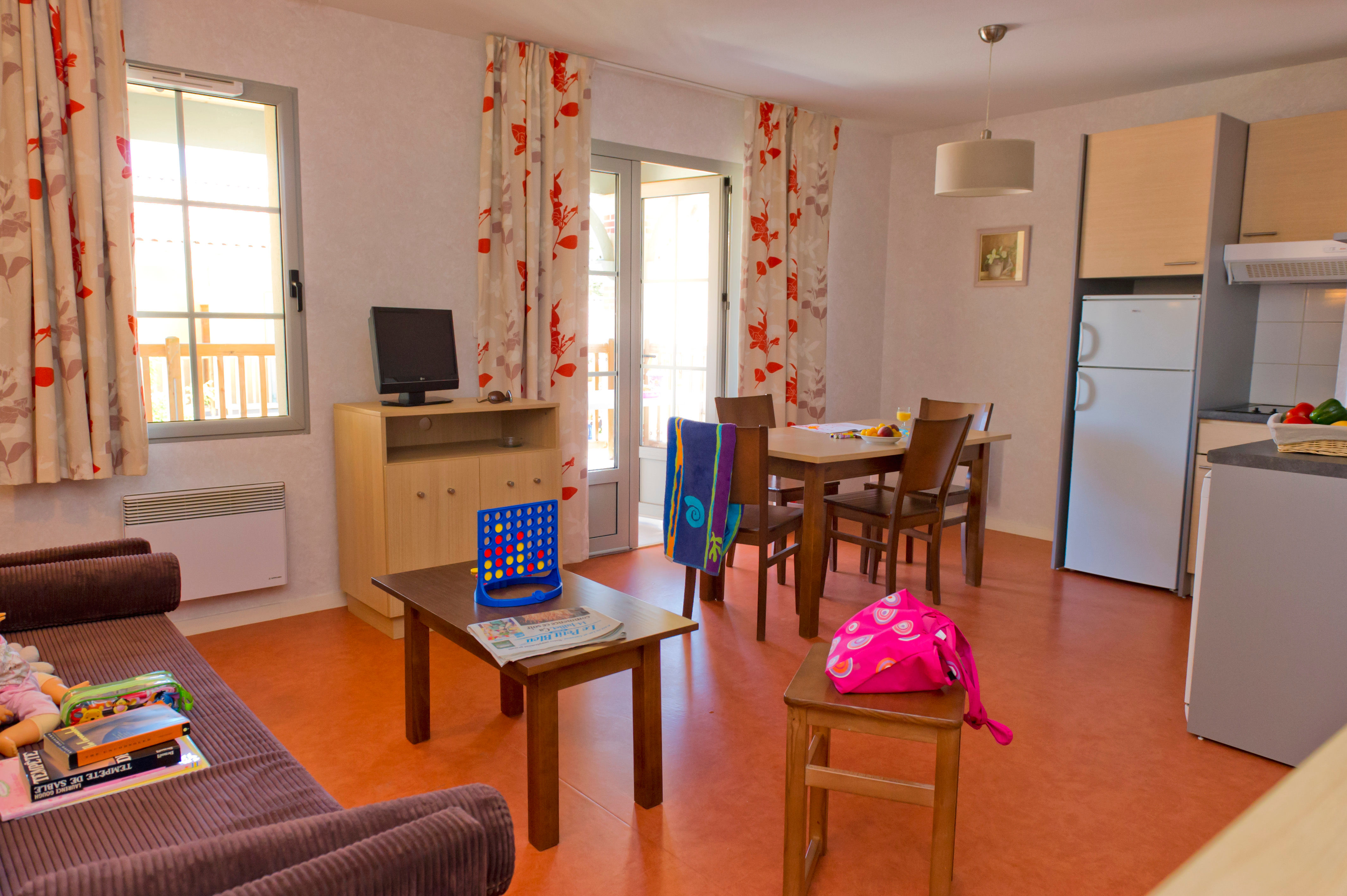 image Terrace doors open up the living area, with the kitchen, fridge, and ceramic hob visible in the corner.