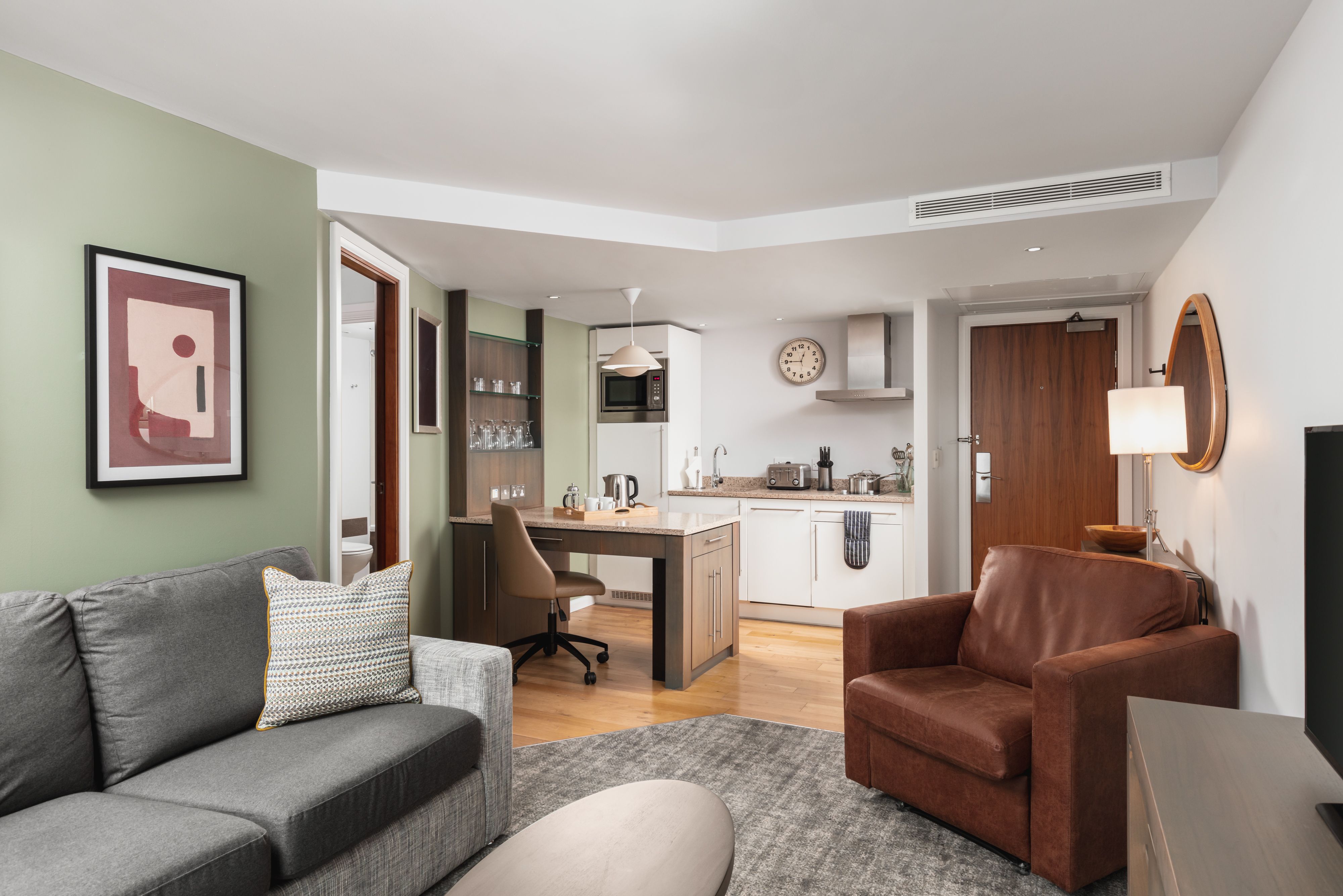 image Open-plan living area with kitchenette, sofa, and dining table.