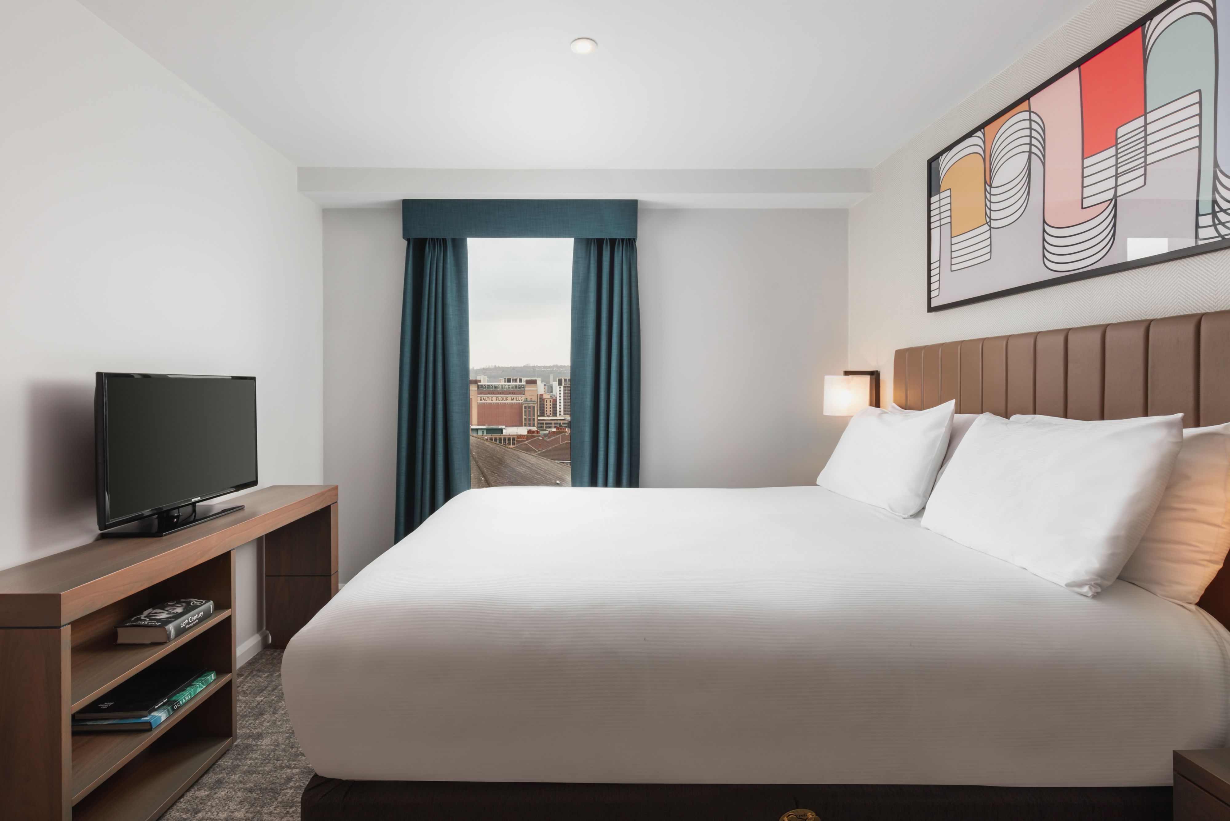 image Bedroom with large bed, flat-screen TV, and curtains.