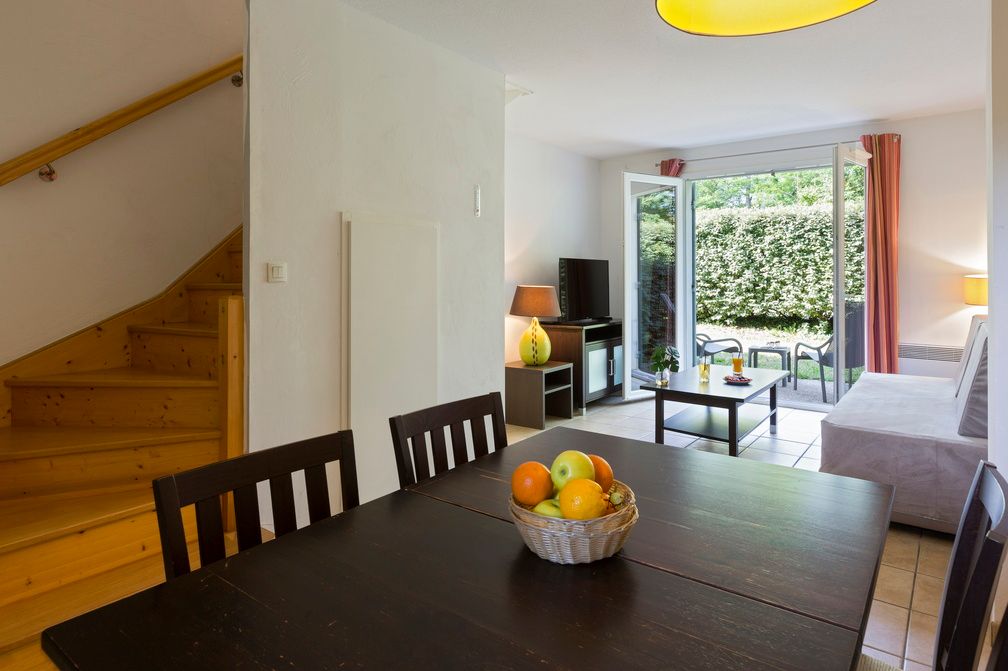 image A spacious open-plan living and dining area with a staircase up to the sleeping levels — and sliding doors leading straight to the terrace.