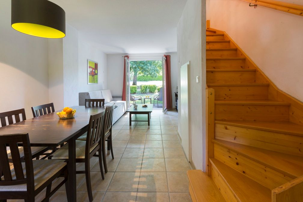 image Spacious communal space at the heart of the apartment — a long dining table for the group, a sofa for unwinding, and stairs up to the sleeping level.