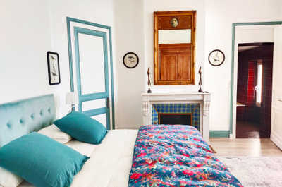 One of the château's bedrooms features a decorative tiled fireplace and a large mirror, reflecting the care taken in the 2020 renovation.