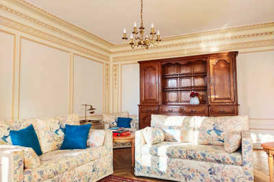 The grand shared lounge, with its chandelier and decorative molding, brings both suites together in this fully private-hire estate.