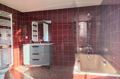 One of two bathrooms, fitted with a bathtub shower combo, and heated towel rail — shared between the rooms of each suite.