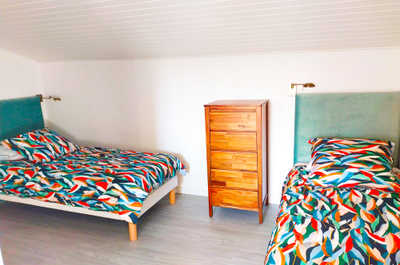 A twin bedroom with colourful bedding and a sloped ceiling, part of the suite parentale sleeping configuration for up to four guests.
