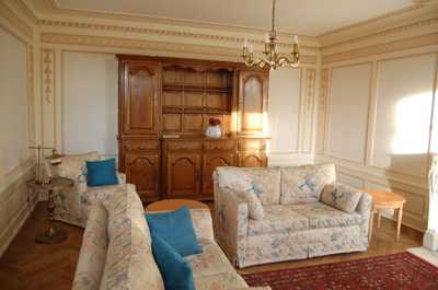 Ornate molding, a chandelier, and generous natural light give the shared living space a classic Bordelais character.