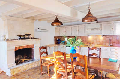 The fully equipped kitchen features exposed beams, copper pendant lights, and a large dining table where the whole group can gather.