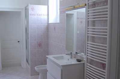 The second bathroom features a walk-in shower, tall window, and heated towel rail, shared across the suite familiale bedrooms.