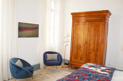 A spacious bedroom with dual seating, a flat-screen television, and tall windows opening to the estate grounds.