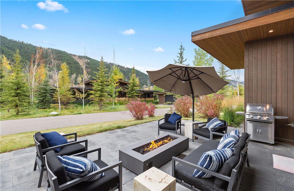 image Outdoor patio with black lounge chairs around a stone fire pit — mountain views and open sky beyond