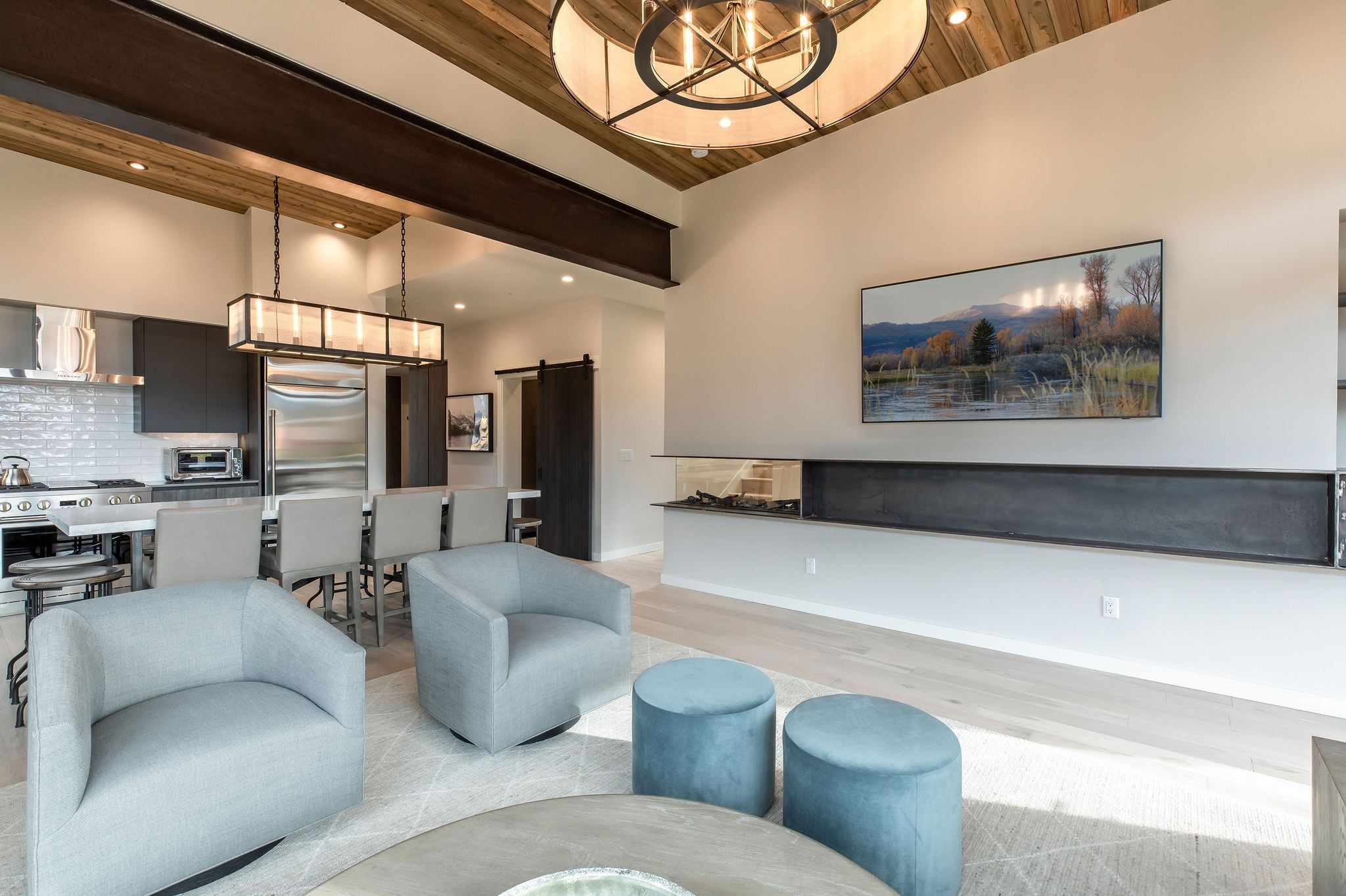 image Living space with relaxing chairs, a mounted TV, and dark kitchen cabinetry beyond