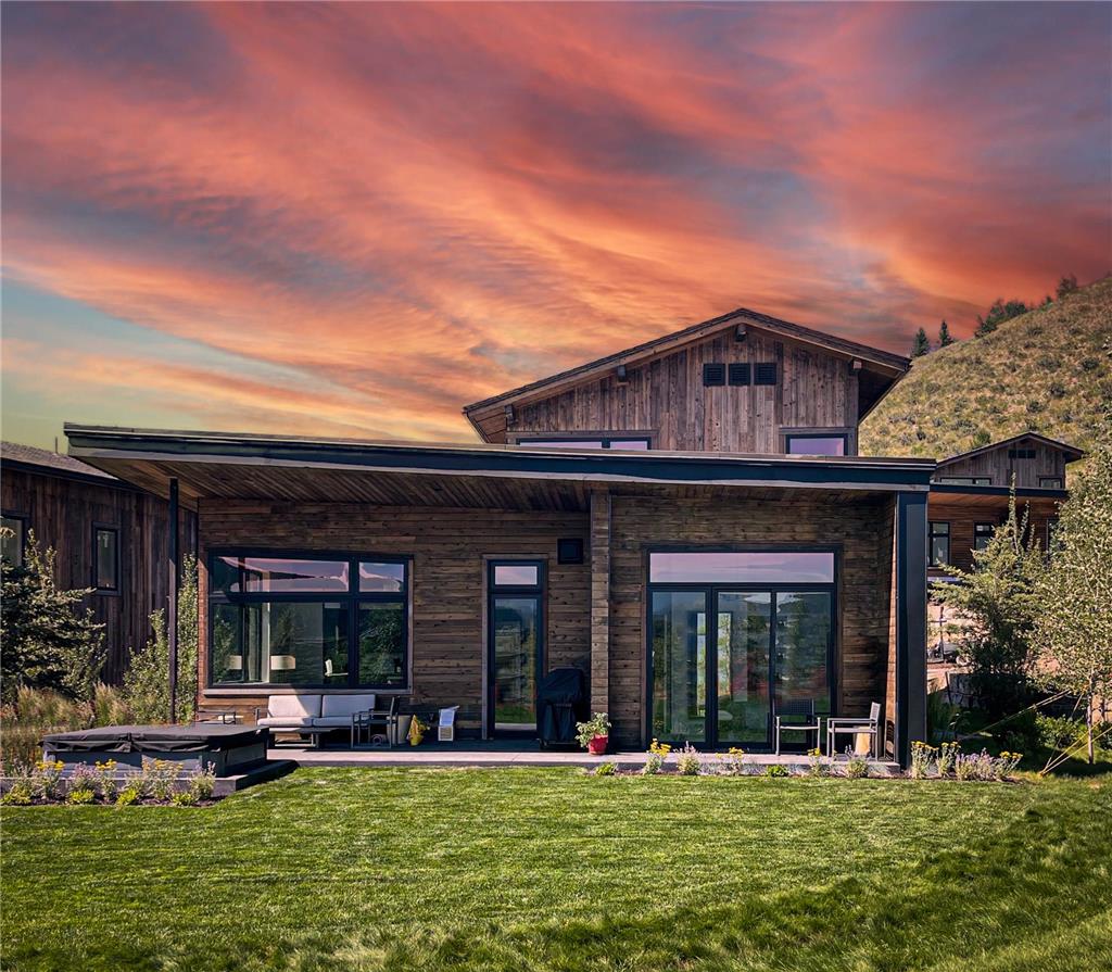 image Cabin exterior at sunset, with mixed wood siding and a hillside backdrop