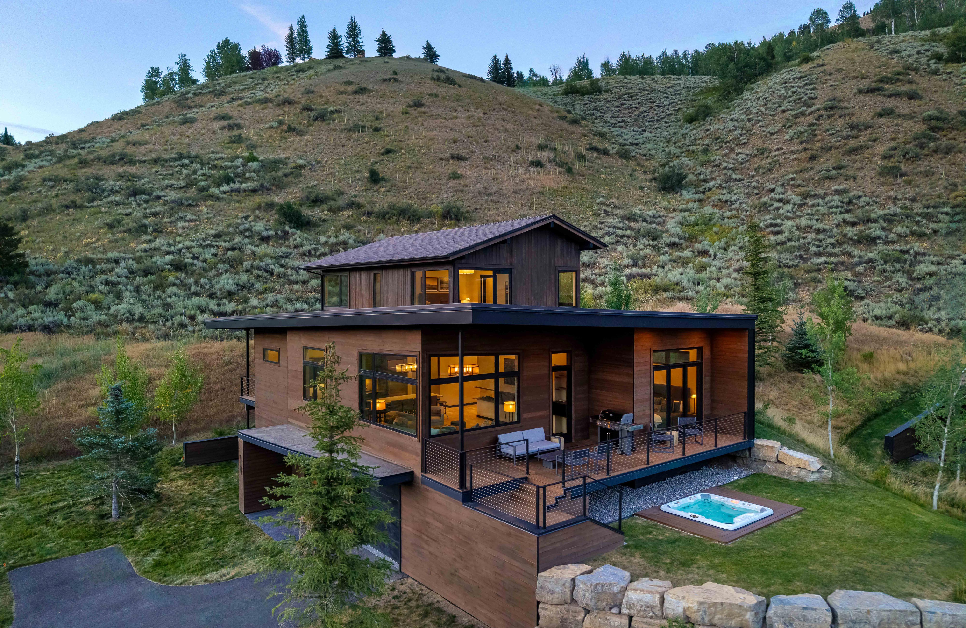 image Aerial view of the cabin exterior with a wood facade and patio furniture set into the hillside