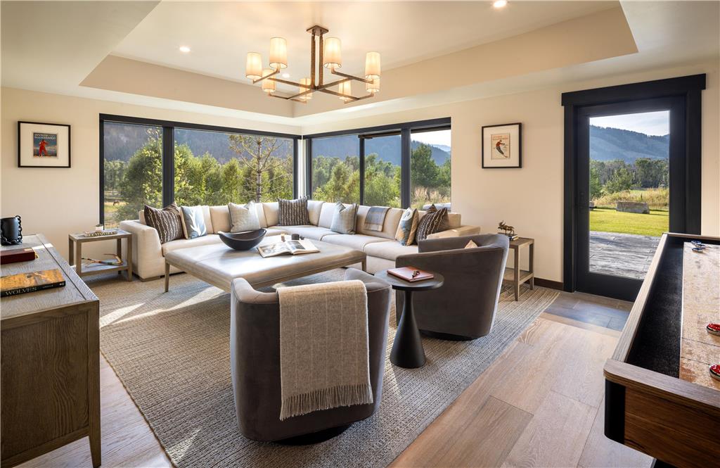 image Recreational room with a grey sectional, accent chairs, and three large windows overlooking the fields and mountains