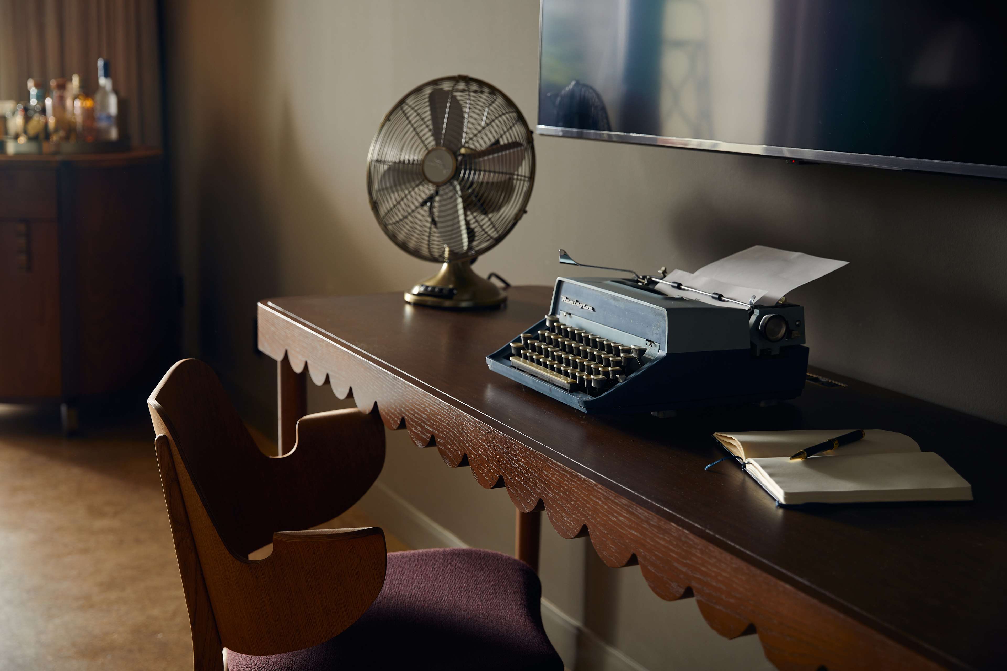 image Mahogany desk with a vintage typewriter and decorative fan, set beside large windows framing city views