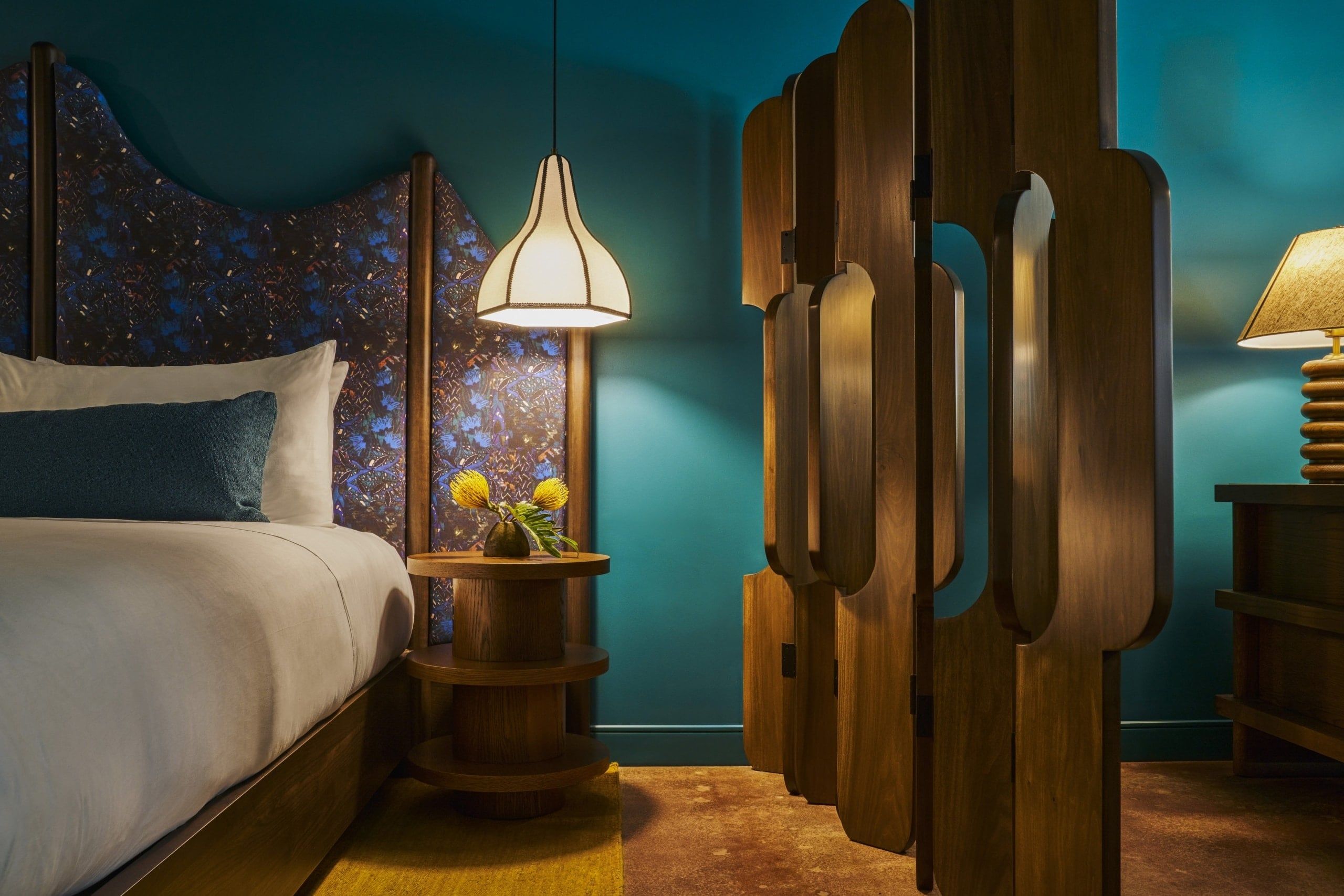 image Close-up of the unique headboard and soft bedding, complemented by a circular nightstand adorned with fresh blooms
