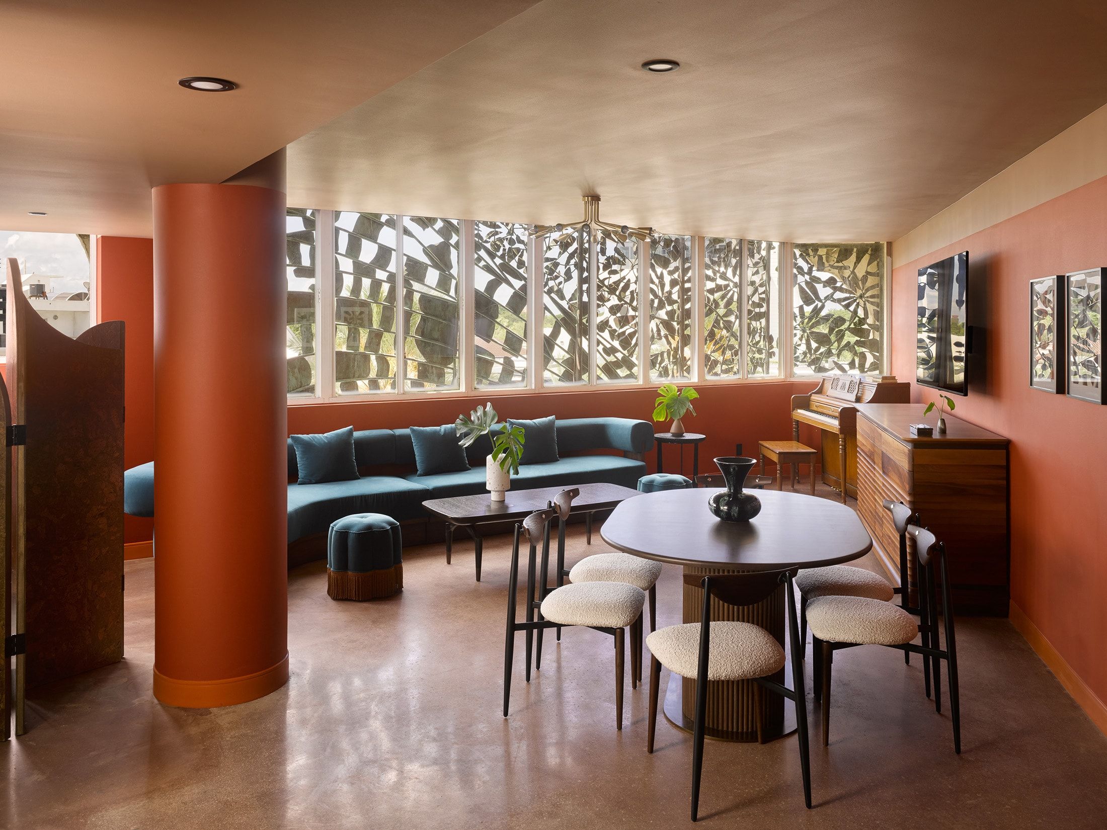 image The living space draws natural light through arched window frames, with a sectional sofa and dining area beyond