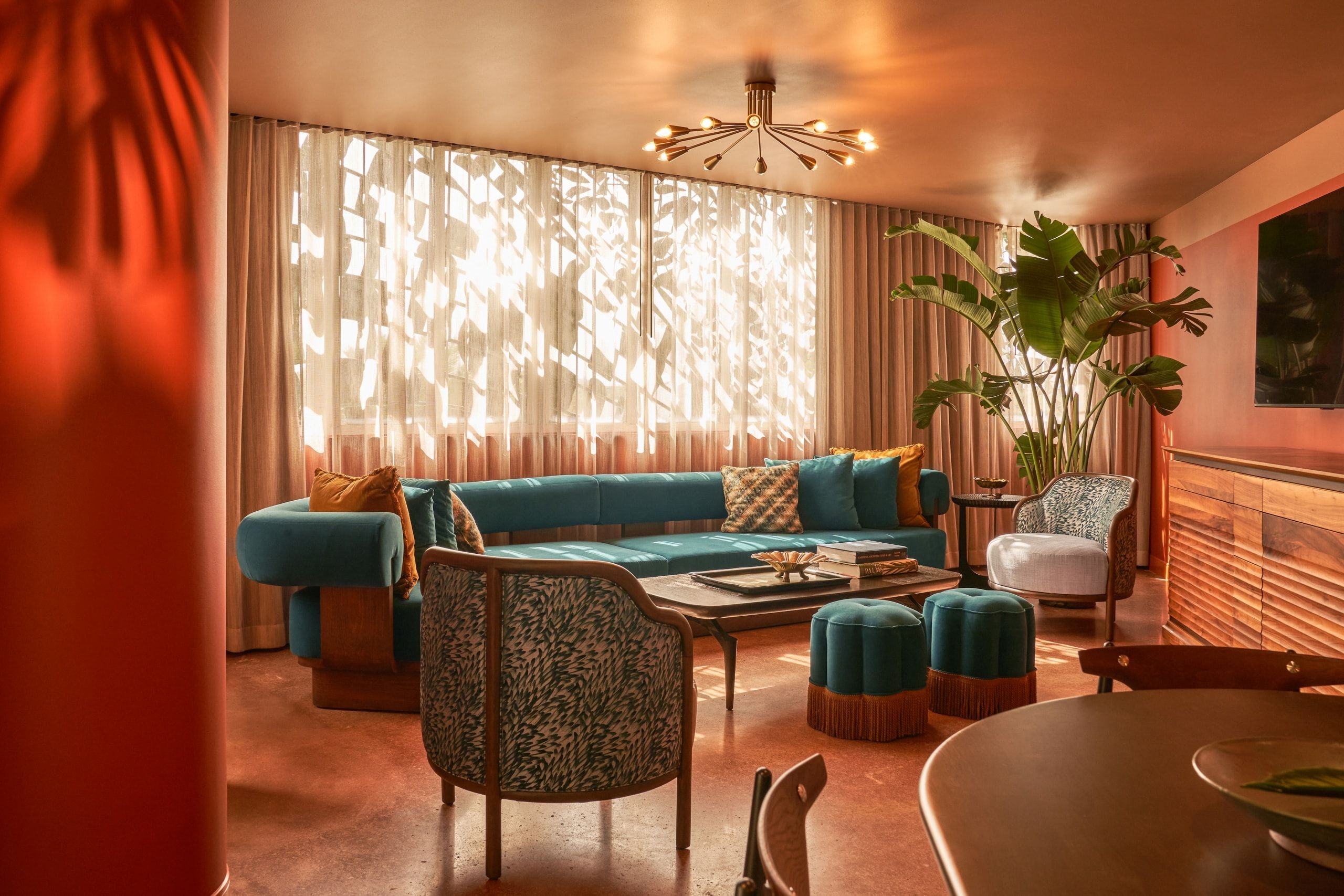 image Curved blue sofa with eclectic accent pillows fills the living area beneath a sculptural light fixture