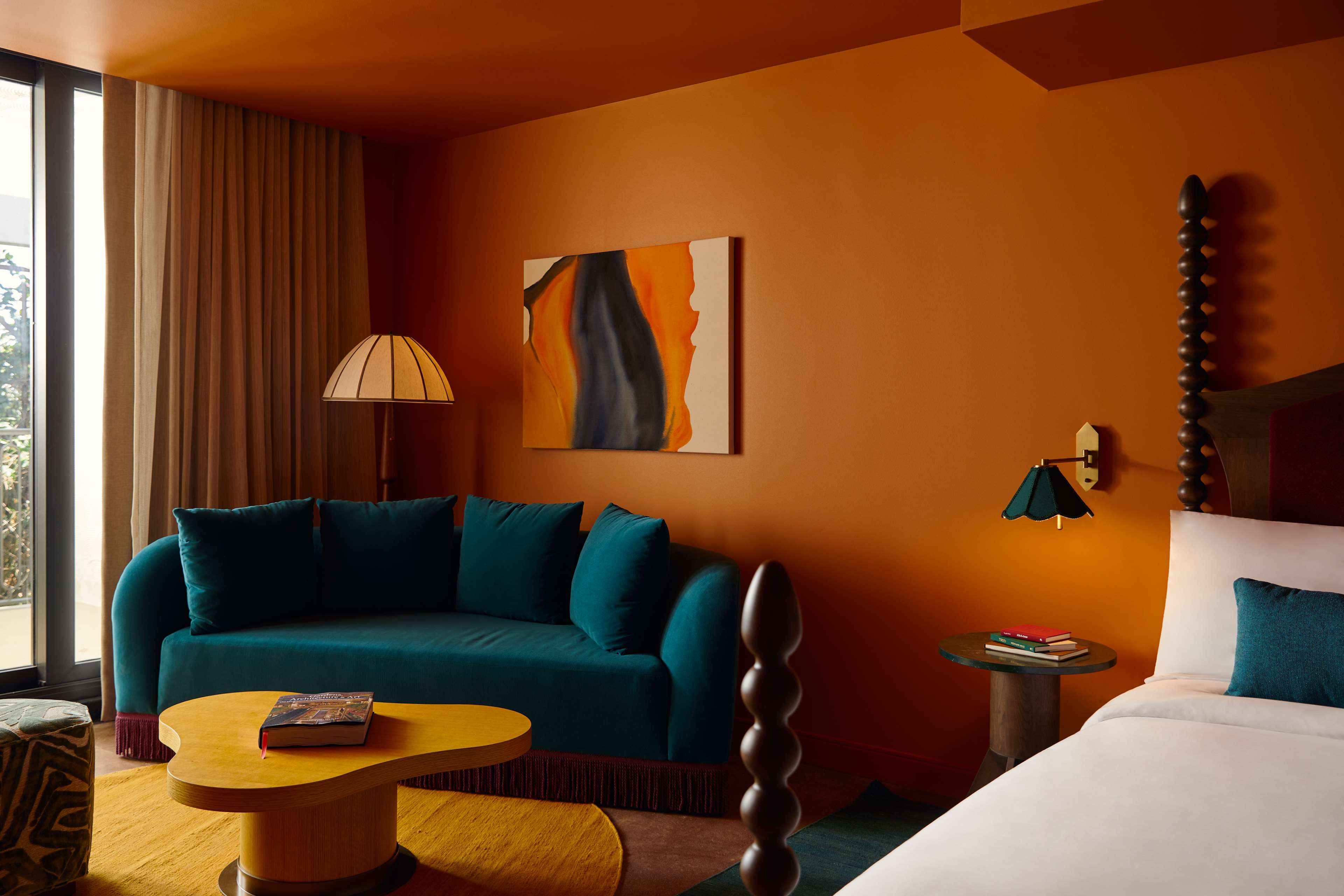 image Rich orange walls enhance the turquoise velvet sofa, inviting relaxation as you unwind with a good book