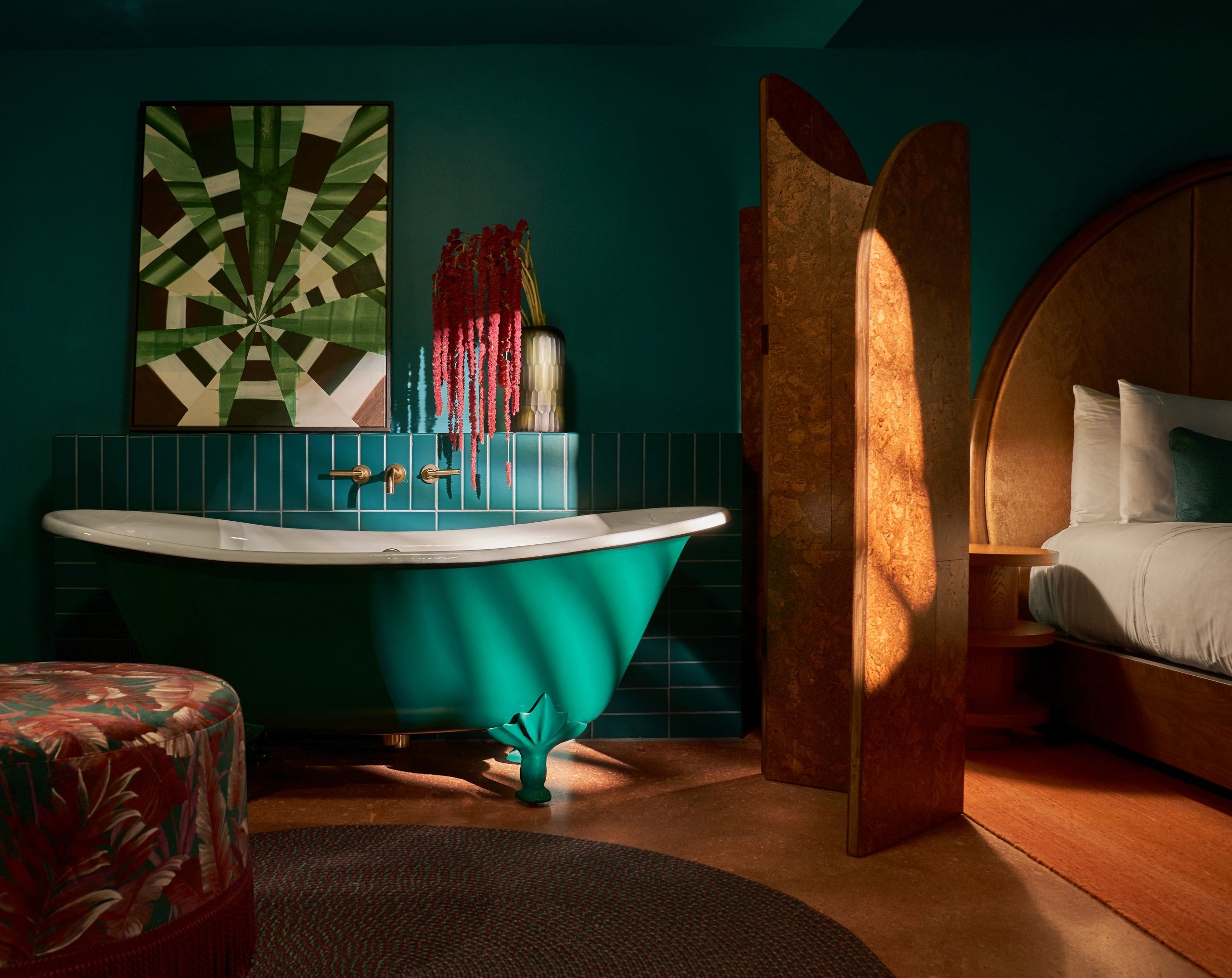 image Clawfoot bathtub in deep teal with gold fittings, set against a wall of bold artwork