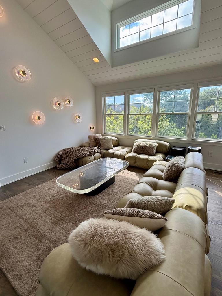 image Relax in this spacious living area, featuring a plush sectional and natural light pouring in from large windows.